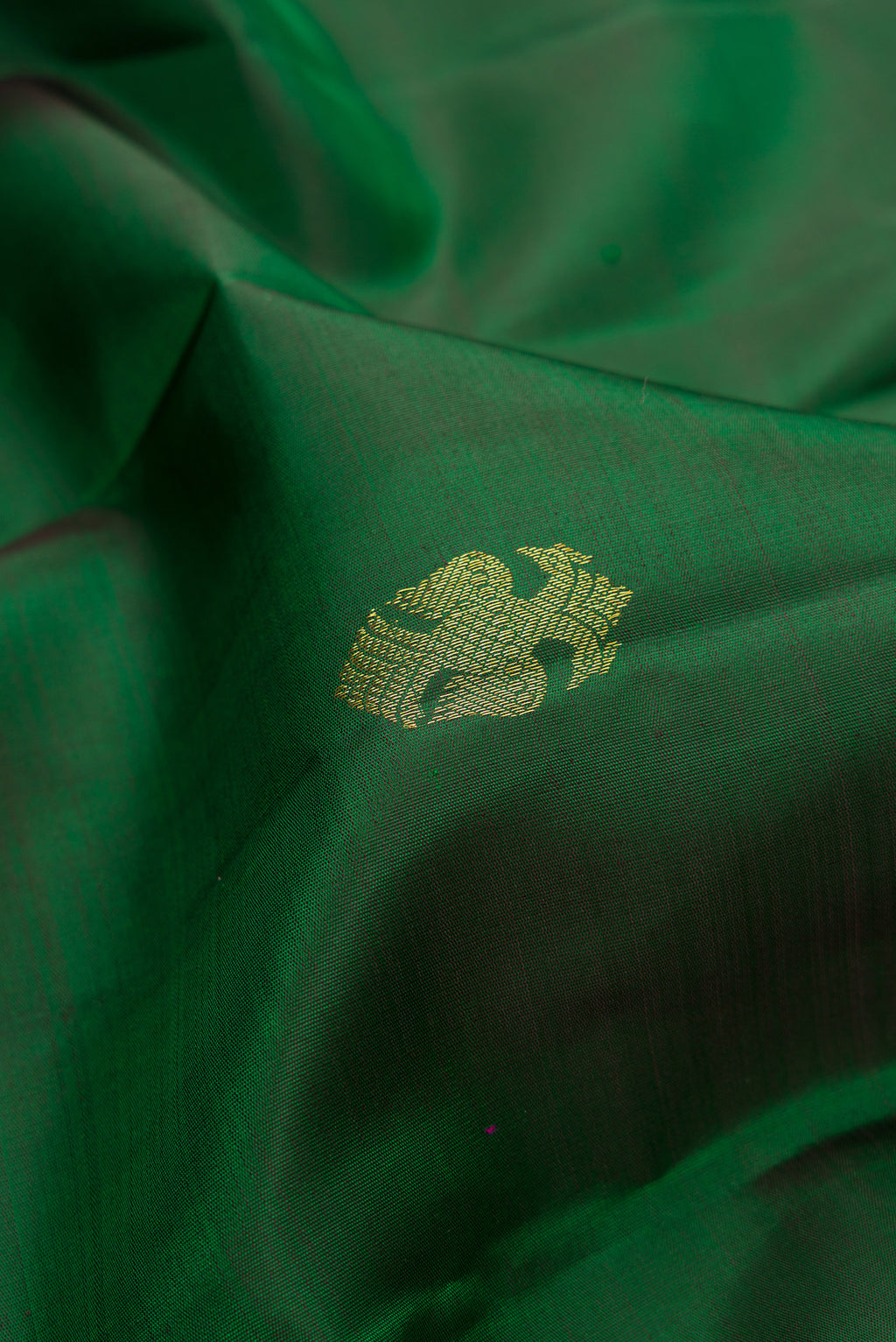 Close up of Bottle Green Kanjivaram Silk Saree with Zari Butta on the body and Fancy Border.  displaying folds