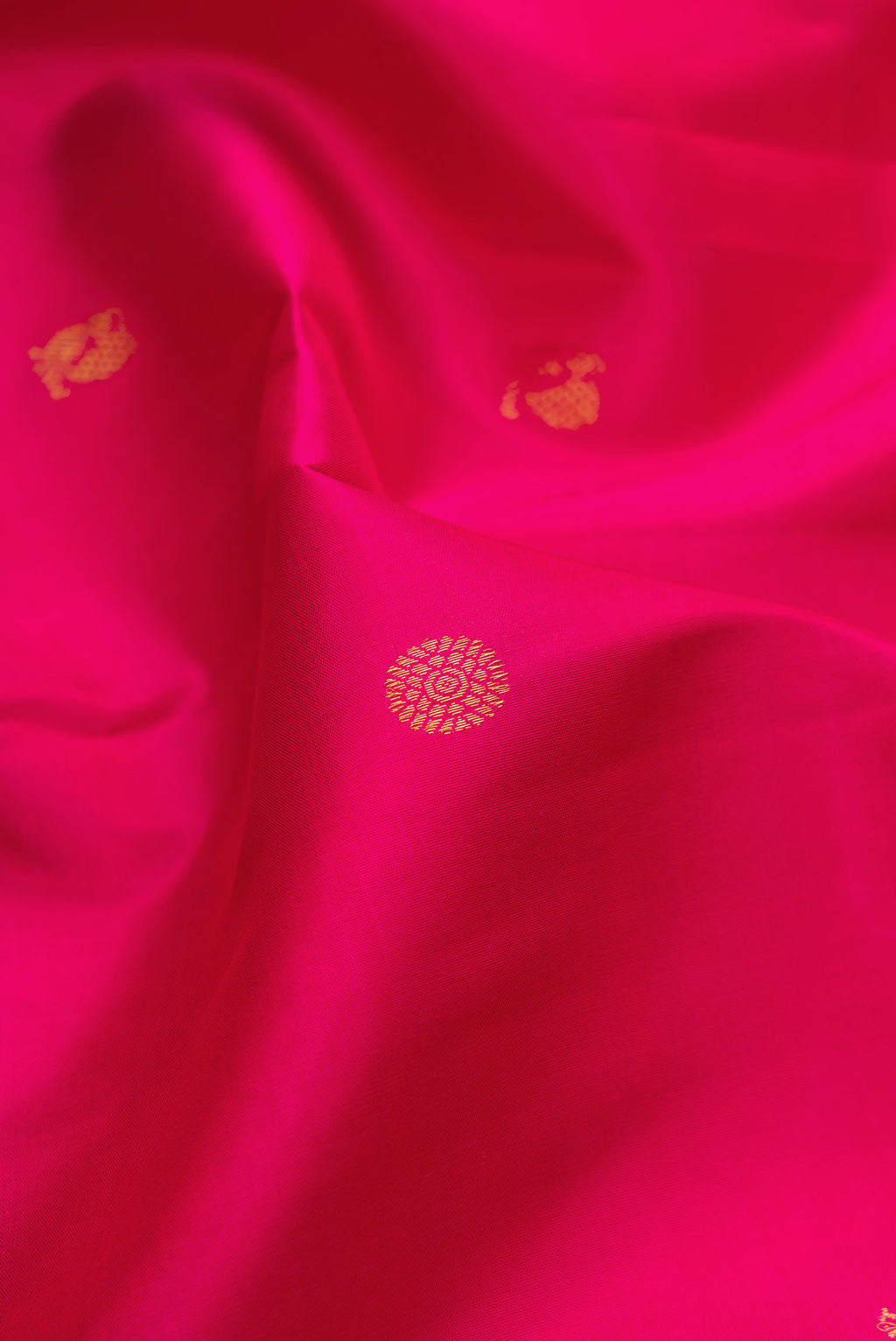 Close up of Dark Pink Kanjivaram Silk Saree with Zari Butta on the body and Zari Border.  displaying folds