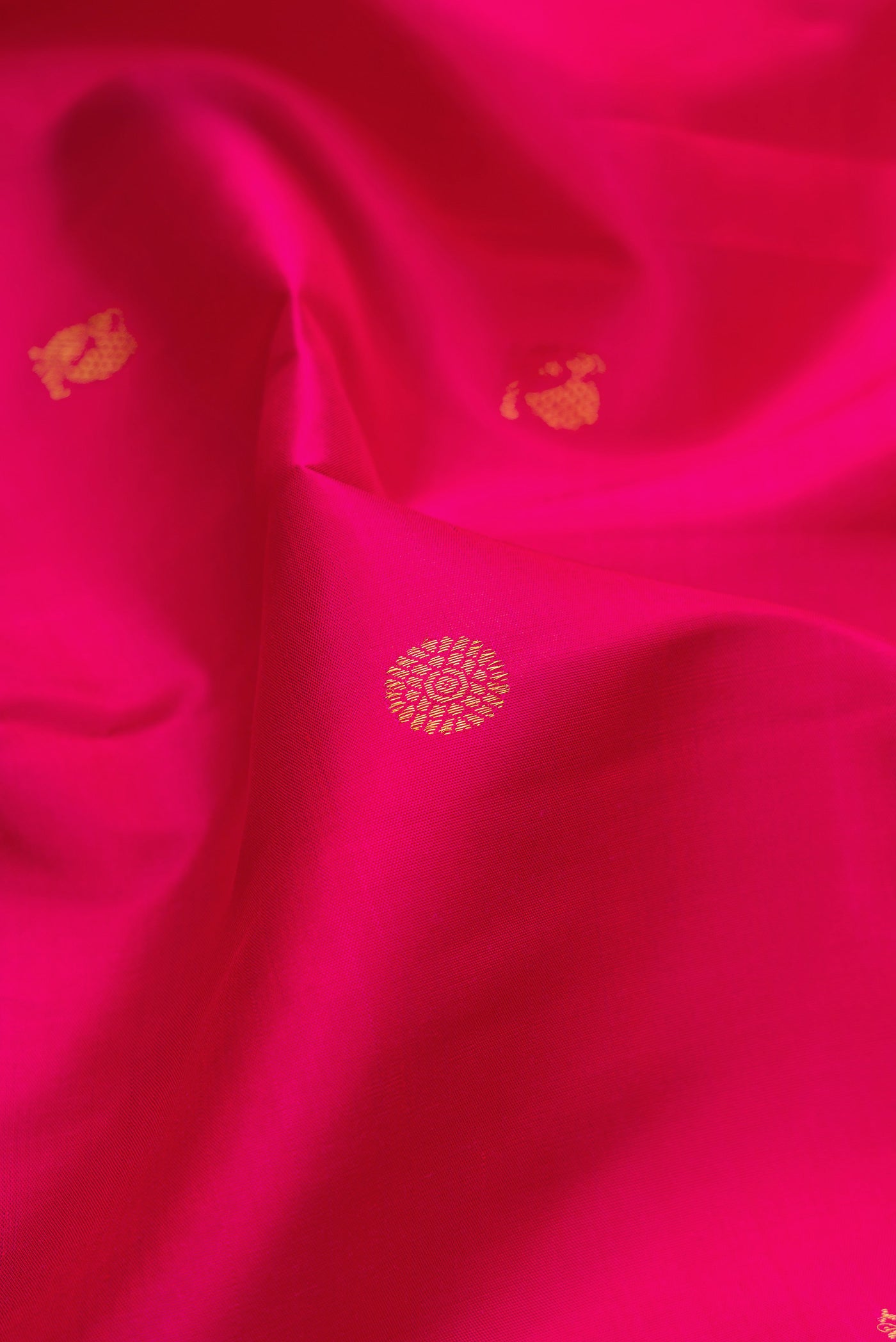 Close up of Dark Pink Kanjivaram Silk Saree with Zari Butta on the body and Zari Border.  displaying folds