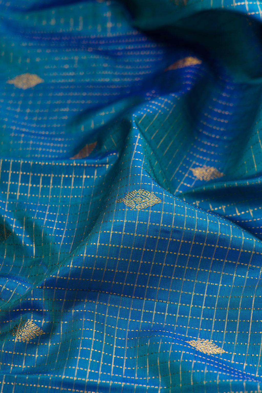 Close up of Peacock Blue Dual Tone Kanjivaram Silk Saree with Checked design on the body and Fancy Border.  displaying folds