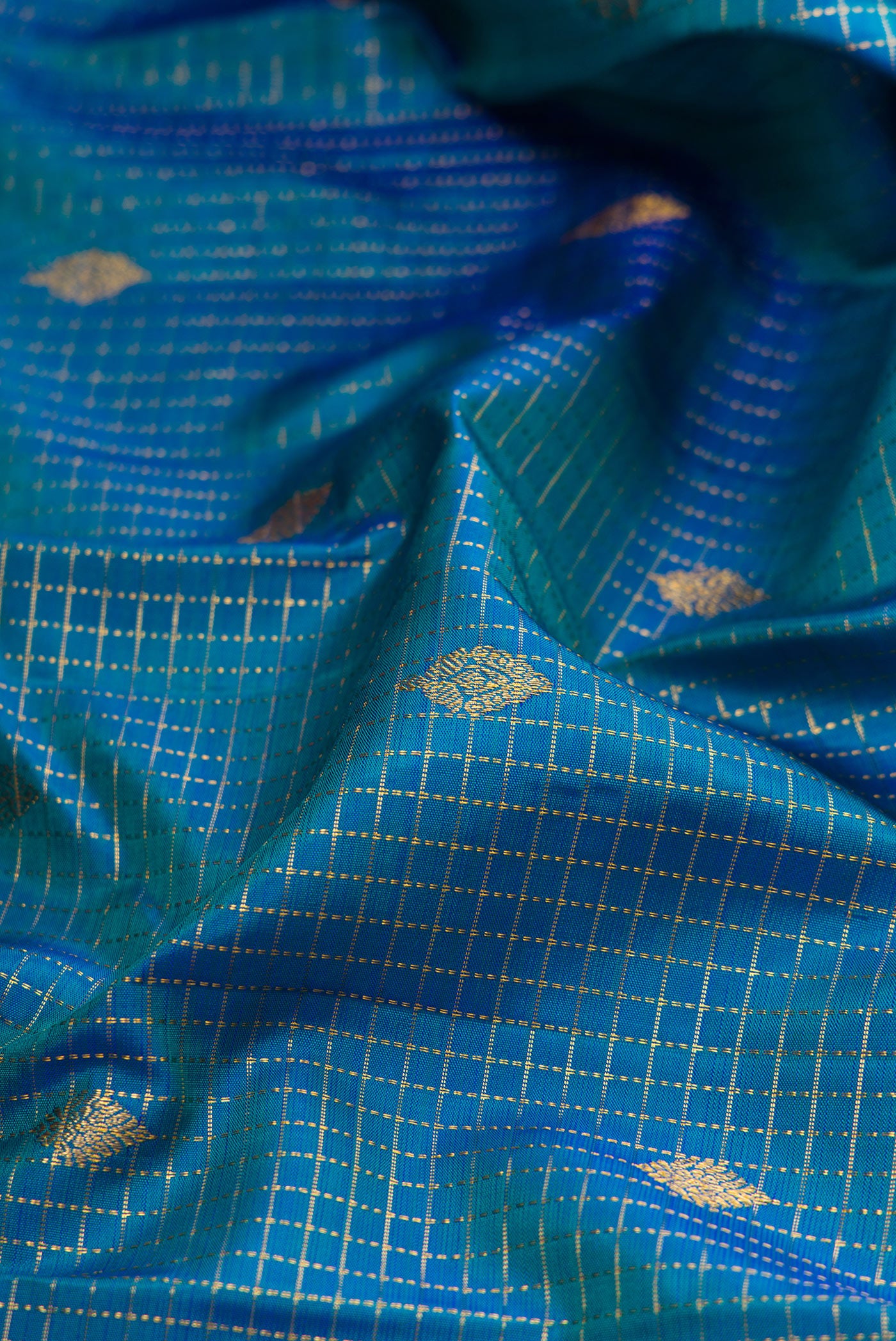 Close up of Peacock Blue Dual Tone Kanjivaram Silk Saree with Checked design on the body and Fancy Border.  displaying folds