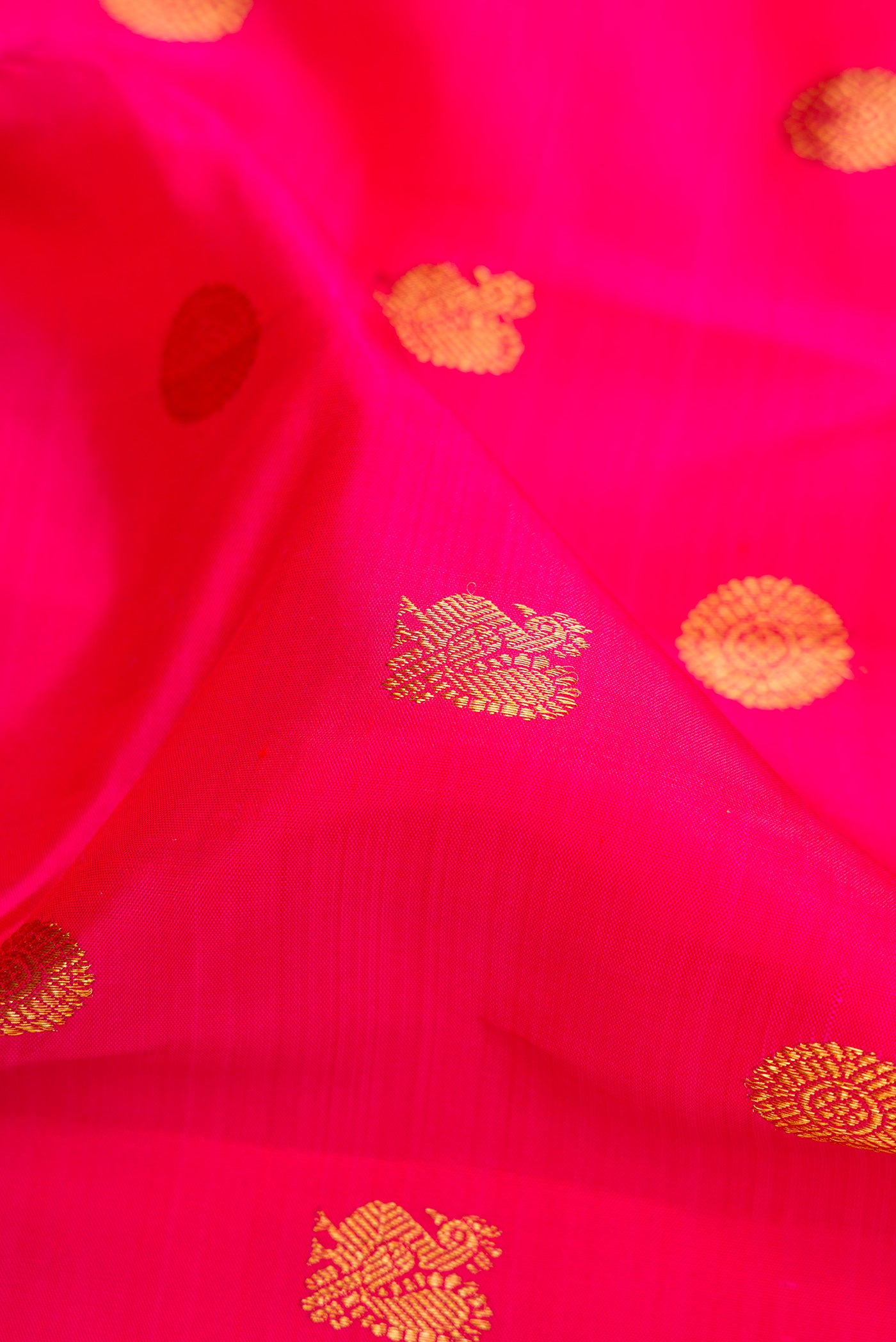 Close up of Dark Pink Kanjivaram Silk Saree with Zari Butta on the body and Zari Border.  displaying folds