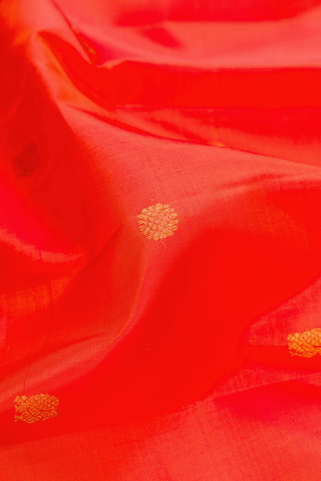 Close up of Orange Kanjivaram Silk Saree with Zari Butta on the body and Zari And Thread Border.  displaying folds