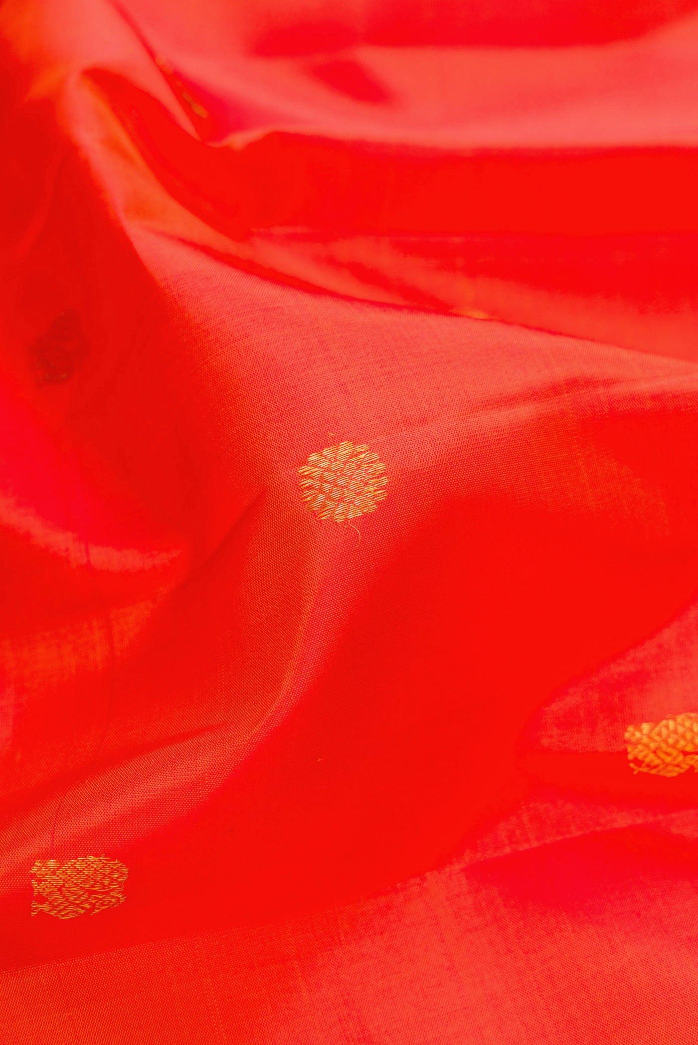 Close up of Orange Kanjivaram Silk Saree with Zari Butta on the body and Zari And Thread Border.  displaying folds