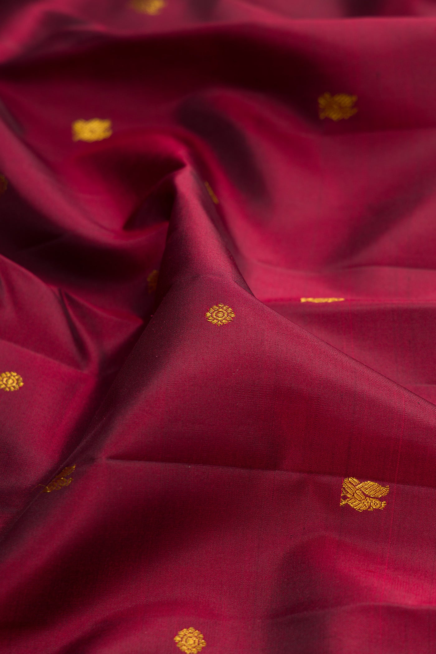 Close up of Maroon Kanjivaram Silk Saree with Zari Butta on the body and Zari Border.  displaying folds