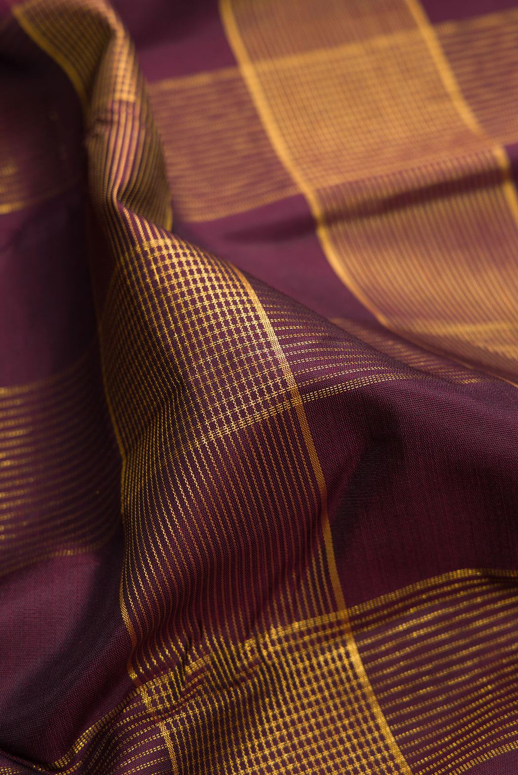 Close up of Burgundy Kanjivaram Silk Saree with Checked design on the body and Zari Border.  displaying folds