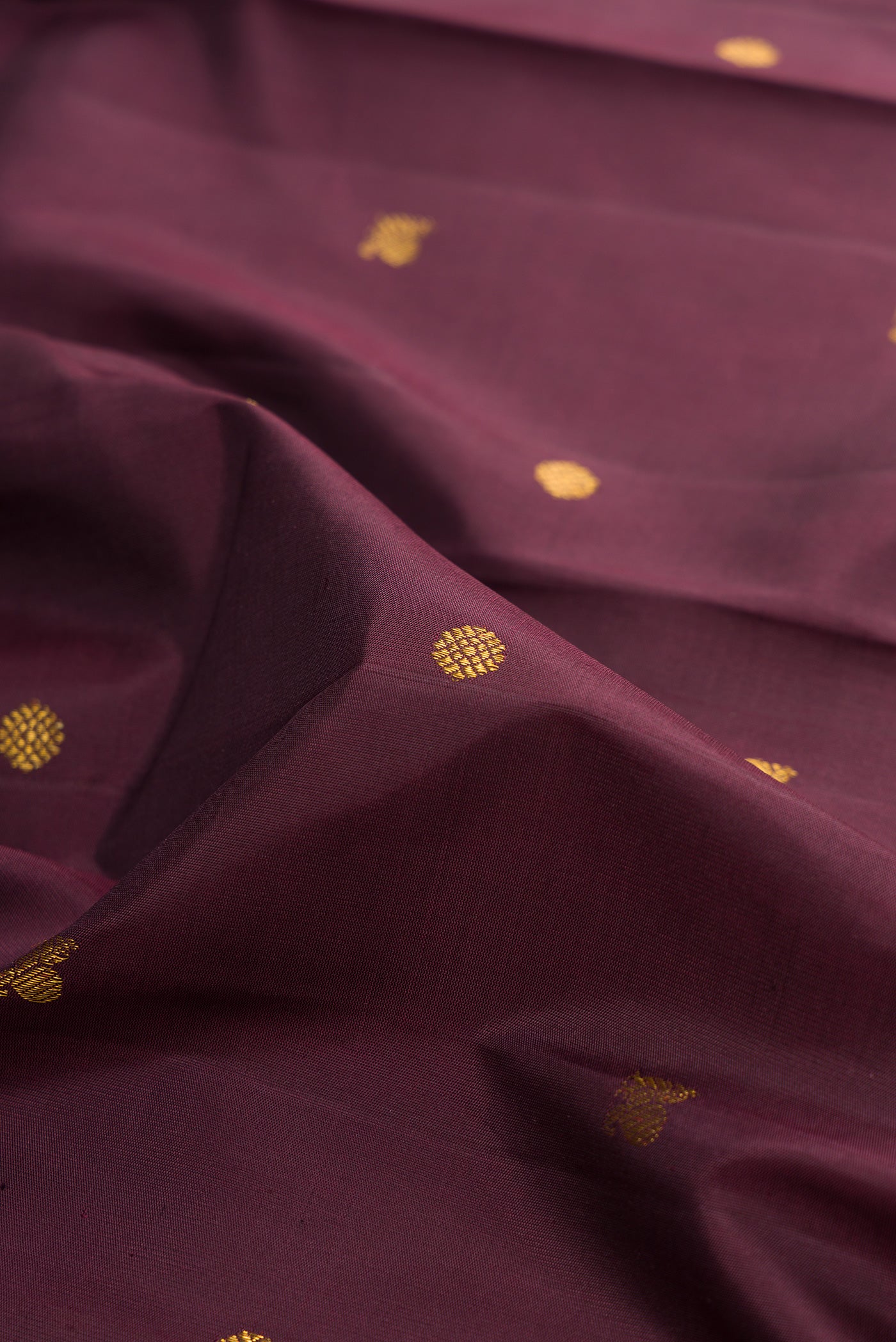Close up of Burgundy Kanjivaram Silk Saree with Zari Butta on the body and Fancy Border.  displaying folds