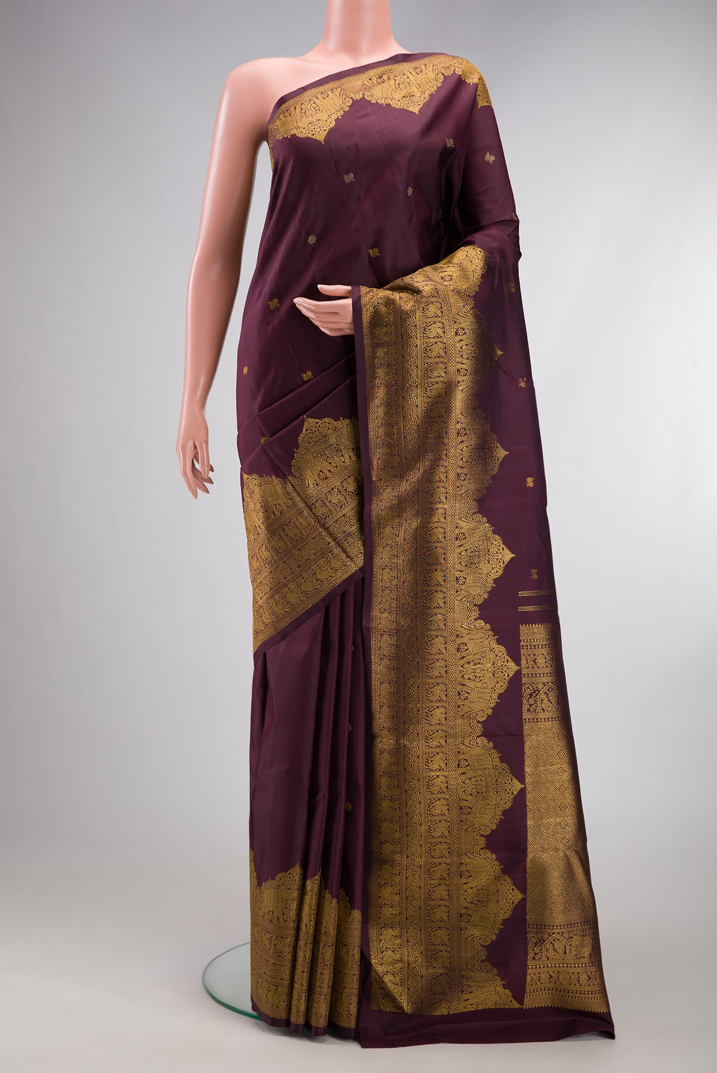 Burgundy Kanjivaram Silk Saree with Zari Butta on the body and Fancy Border.  displayed on a mannequin