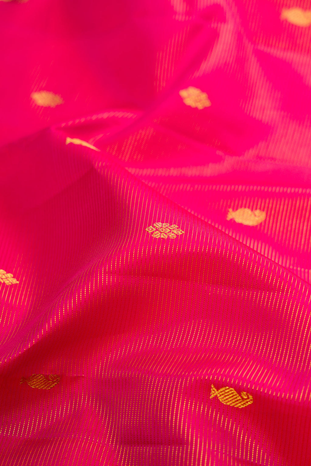 Close up of Rani Pink Kanjivaram Silk Saree with Zari Butta on the body and Zari Border.  displaying folds