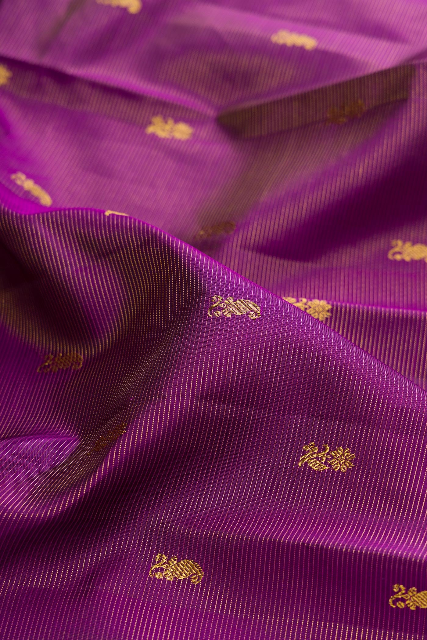 Close up of Purple Kanjivaram Silk Saree with Zari Butta on the body and Zari Border.  displaying folds