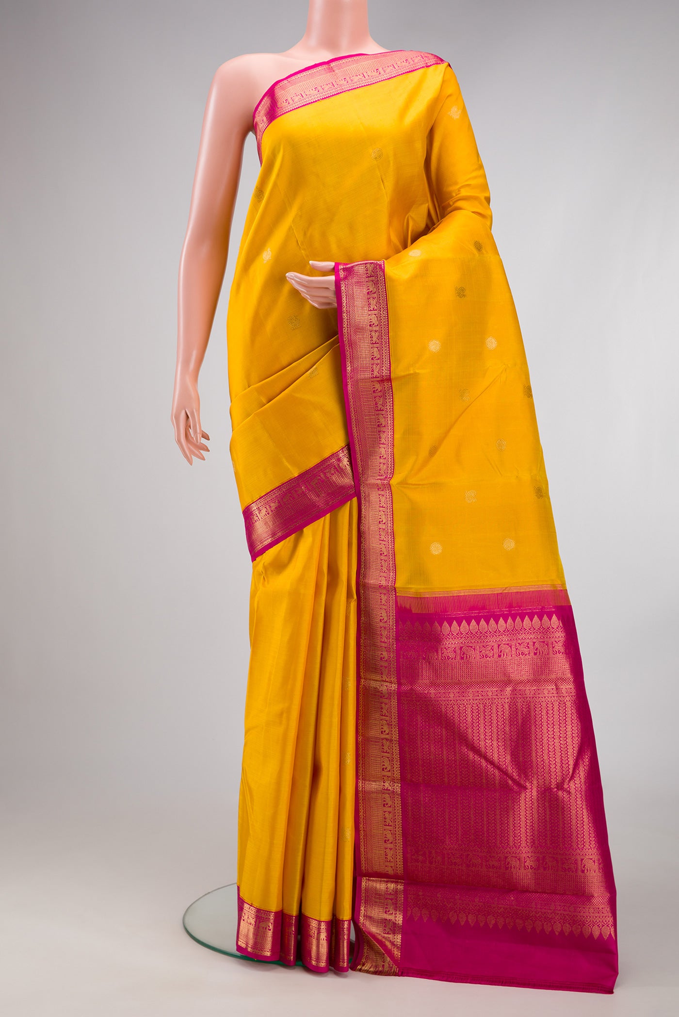 Yellow Kanjivaram Silk Saree with Zari Butta on the body and Zari Border.  displayed on a mannequin