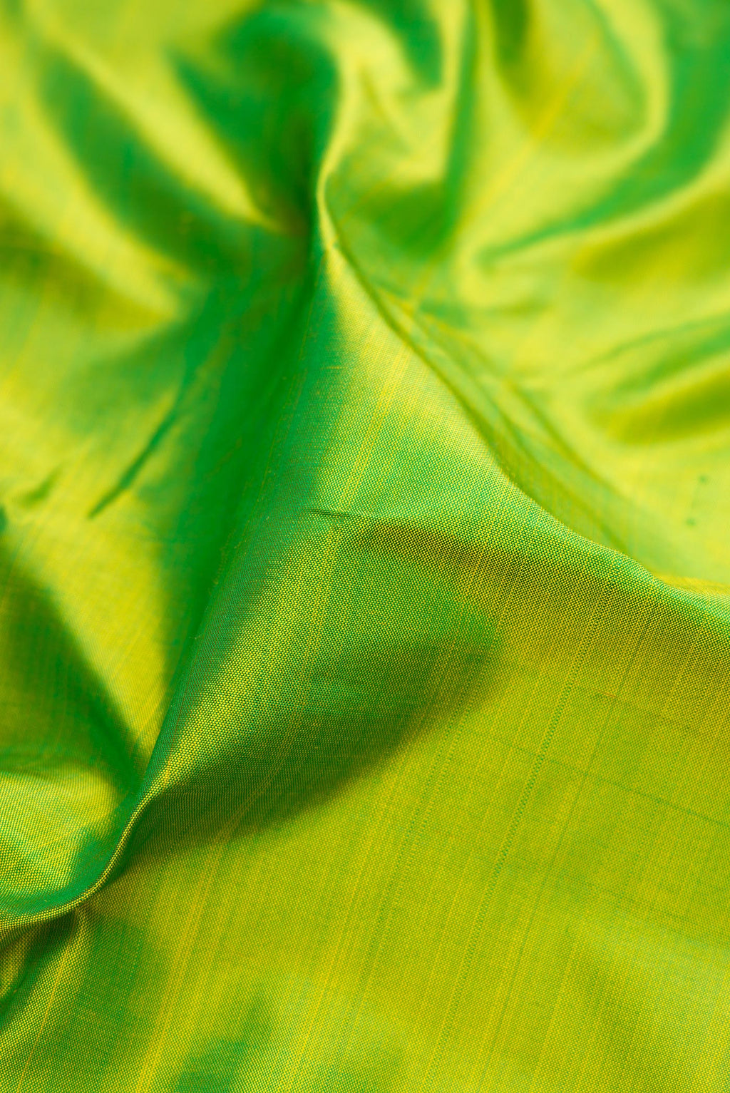 Close up of Parrot Green Kanjivaram Silk Saree with Plain Body and Zari Border.  displaying folds