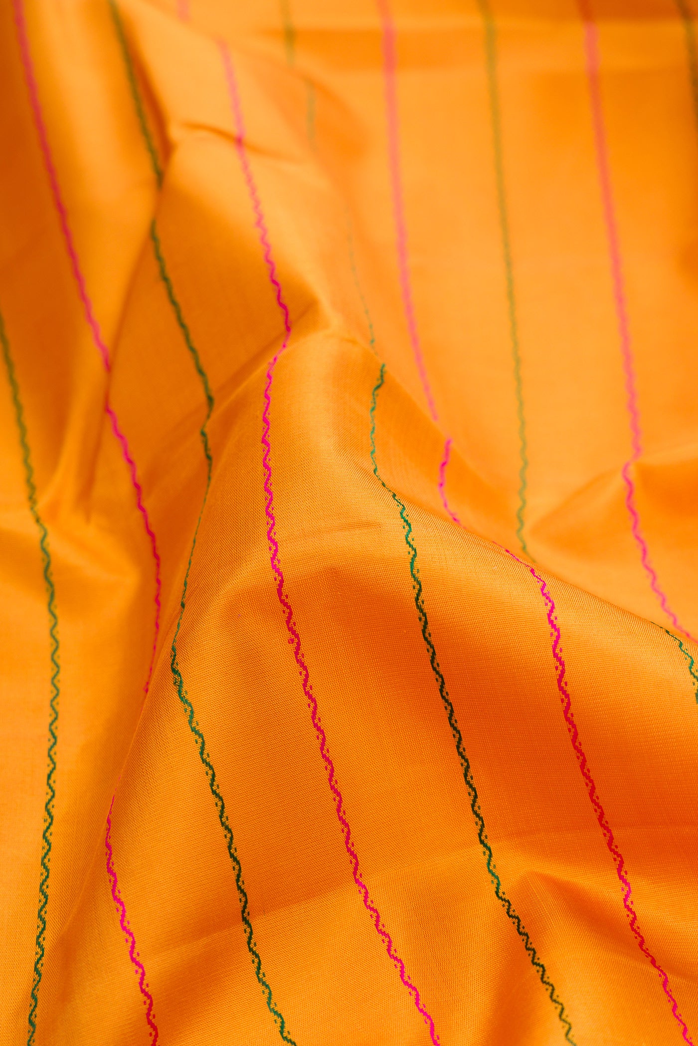 Close up of Mustard Kanchipuram Silk Saree with Veldhari on the body and Ganga Jamuna Border.  displaying folds