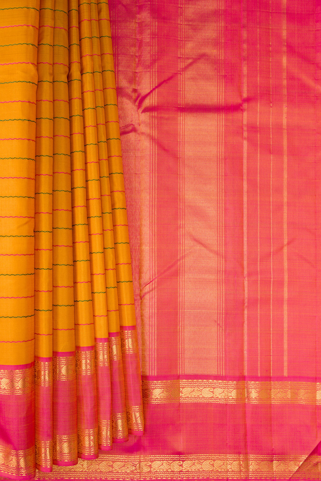 Pleats and pallu of Mustard Kanchipuram Silk Saree with Veldhari on the body and Ganga Jamuna Border. 