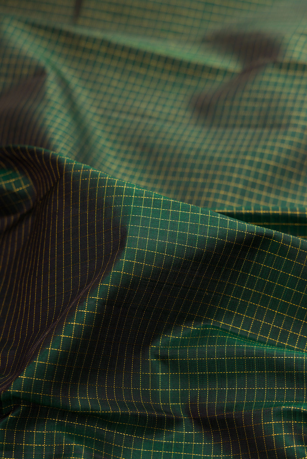 Close up of Pure Silk Bottle Green Kanchipuram Saree with Checked design on the body and Zari Border.  displaying folds