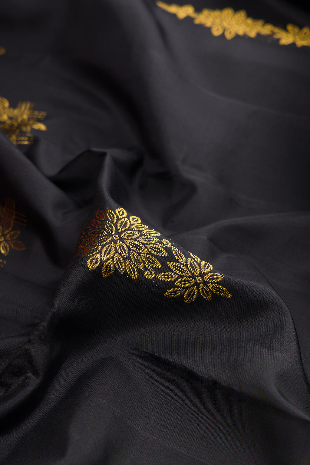Close up of Black Kanjivaram Silk Saree with Zari Butta on the body and Fancy Border.  displaying folds