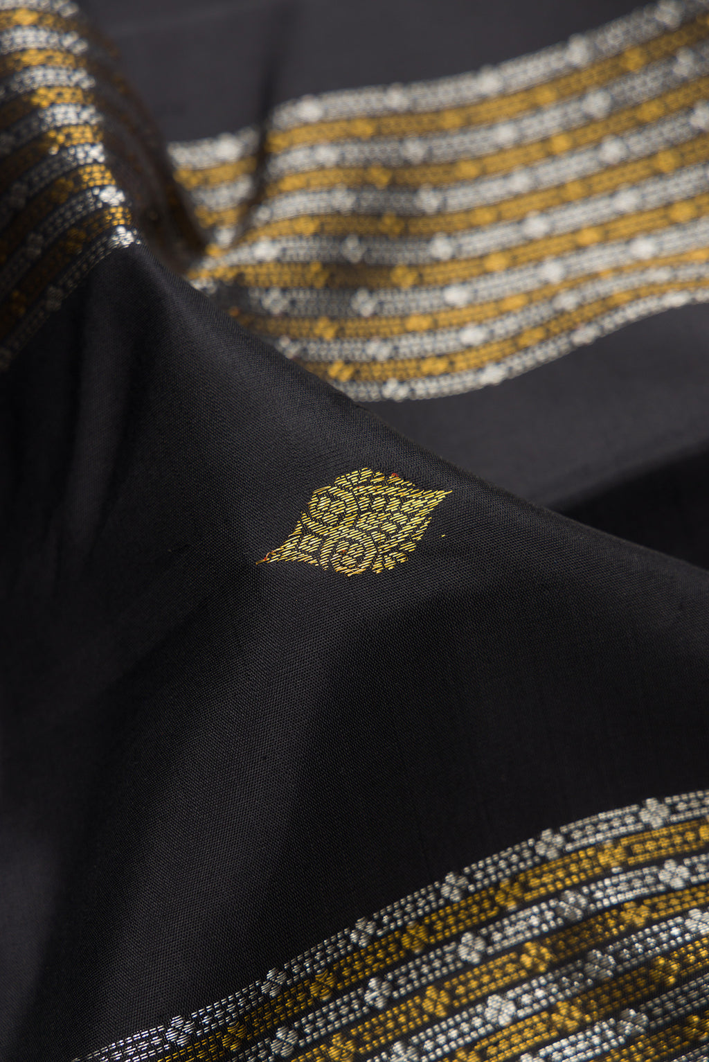 Close up of Black Kanjivaram Silk Saree with Zari Butta on the body and Without Border.  displaying folds