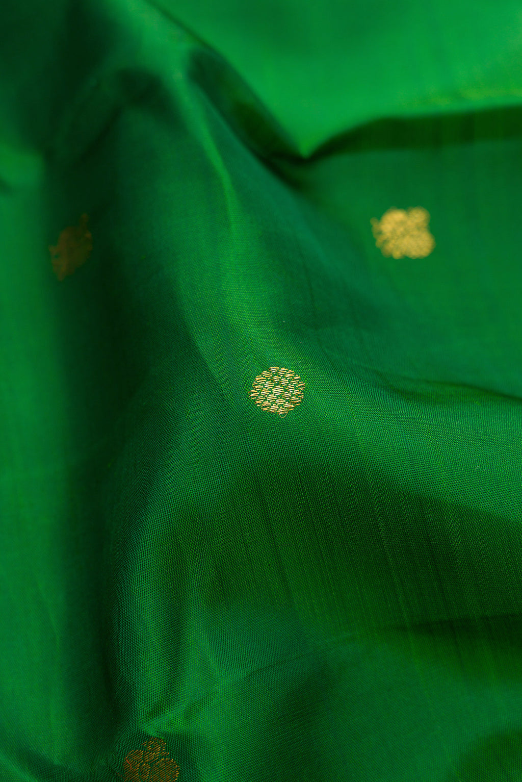 Close up of Green Kanjivaram Silk Saree with Zari Butta on the body and Zari Border.  displaying folds