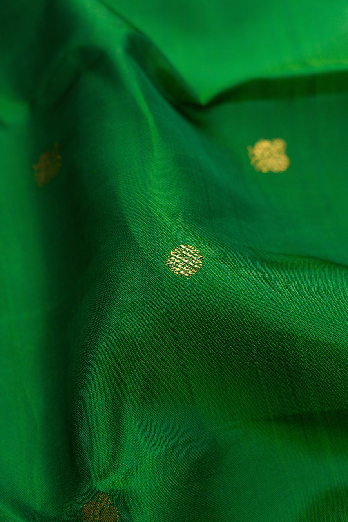 Close up of Green Kanjivaram Silk Saree with Zari Butta on the body and Zari Border.  displaying folds