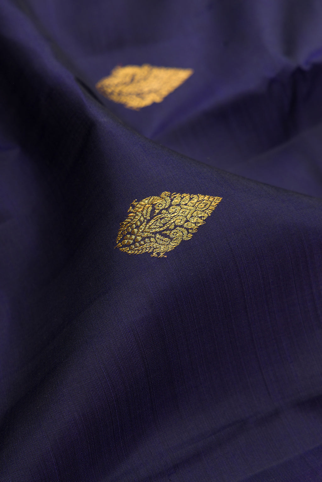 Close up of Navy Blue Kanjivaram Silk Saree with Zari Butta on the body and Fancy Border.  displaying folds