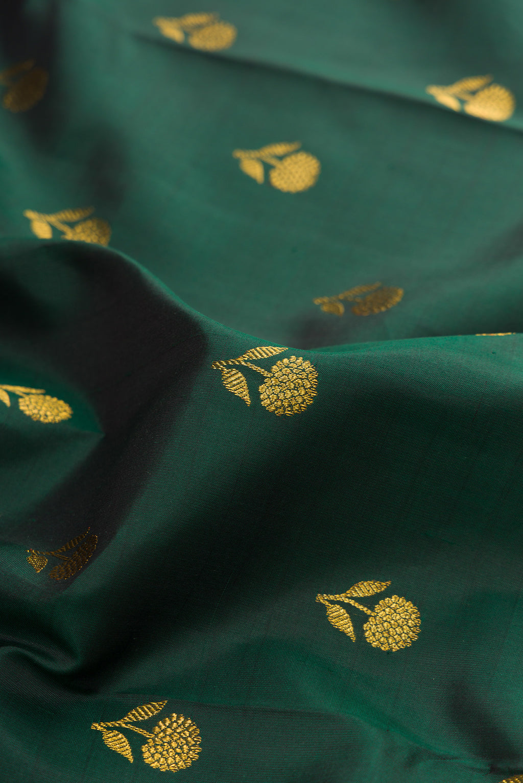 Close up of Bottle Green Kanjivaram Silk Saree with Zari Butta on the body and Fancy Border.  displaying folds