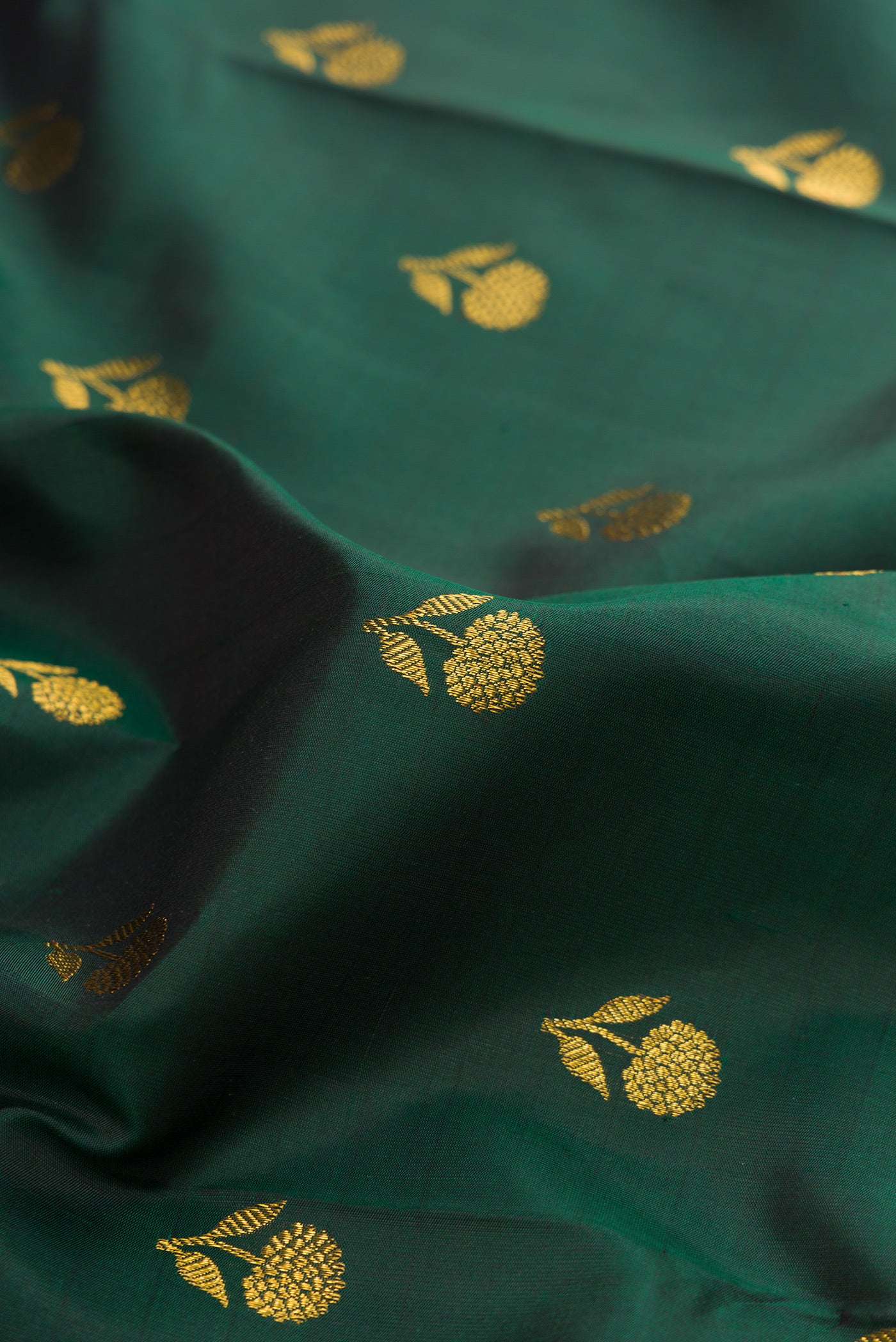 Close up of Bottle Green Kanjivaram Silk Saree with Zari Butta on the body and Fancy Border.  displaying folds