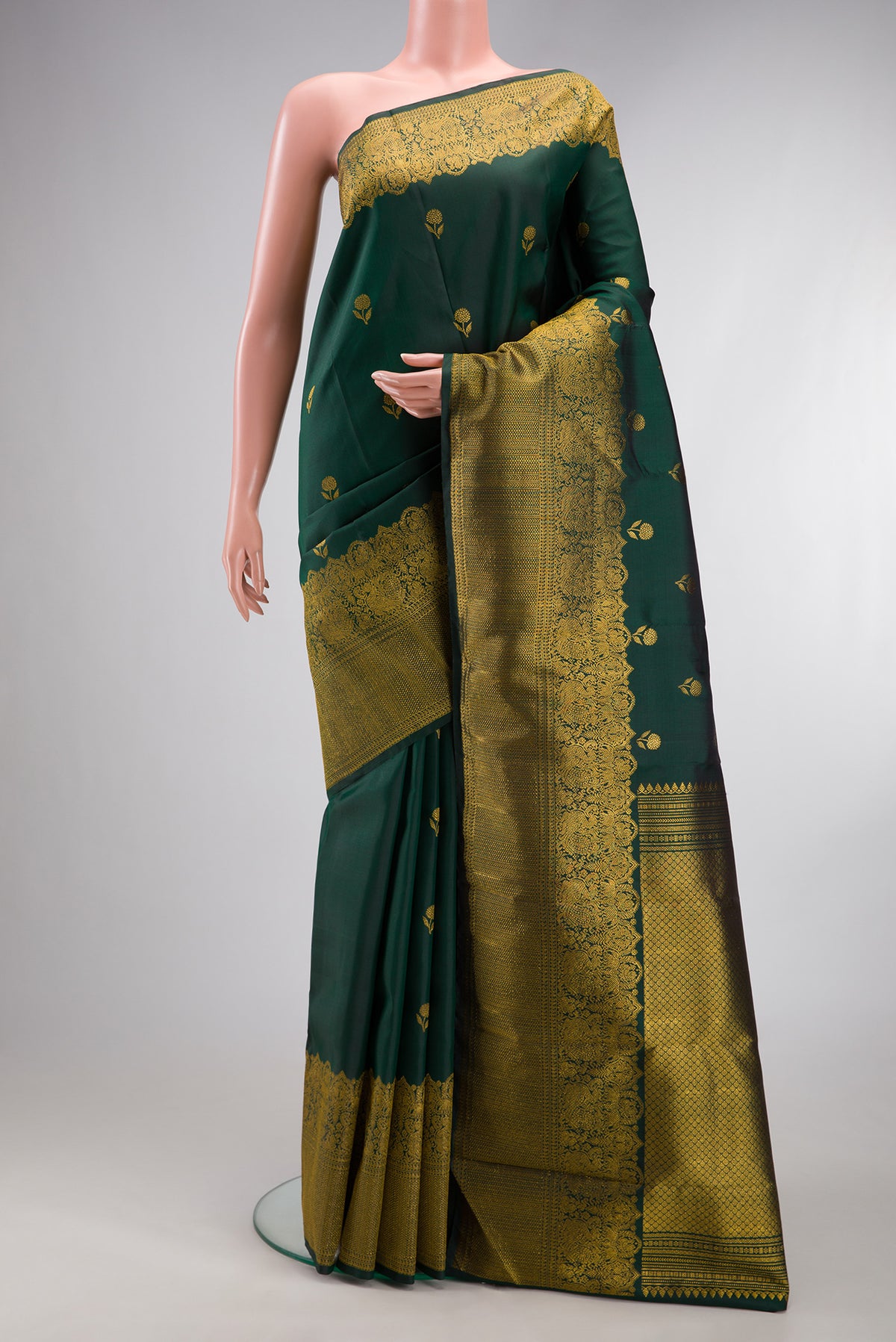 Bottle Green Kanjivaram Silk Saree with Zari Butta on the body and Fancy Border.  displayed on a mannequin