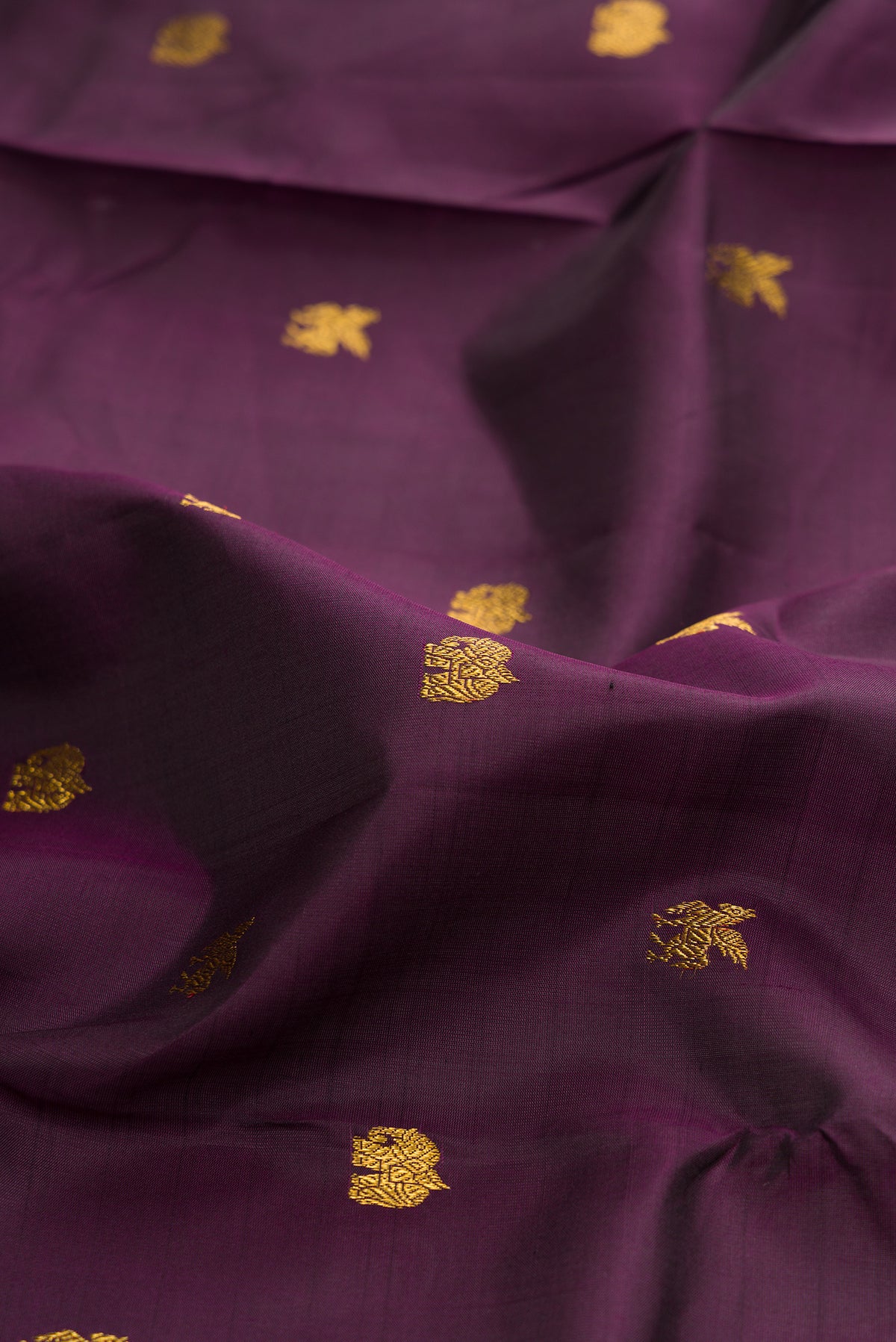 Close up of Burgundy Kanjivaram Silk Saree with Zari Butta on the body and Zari Border.  displaying folds