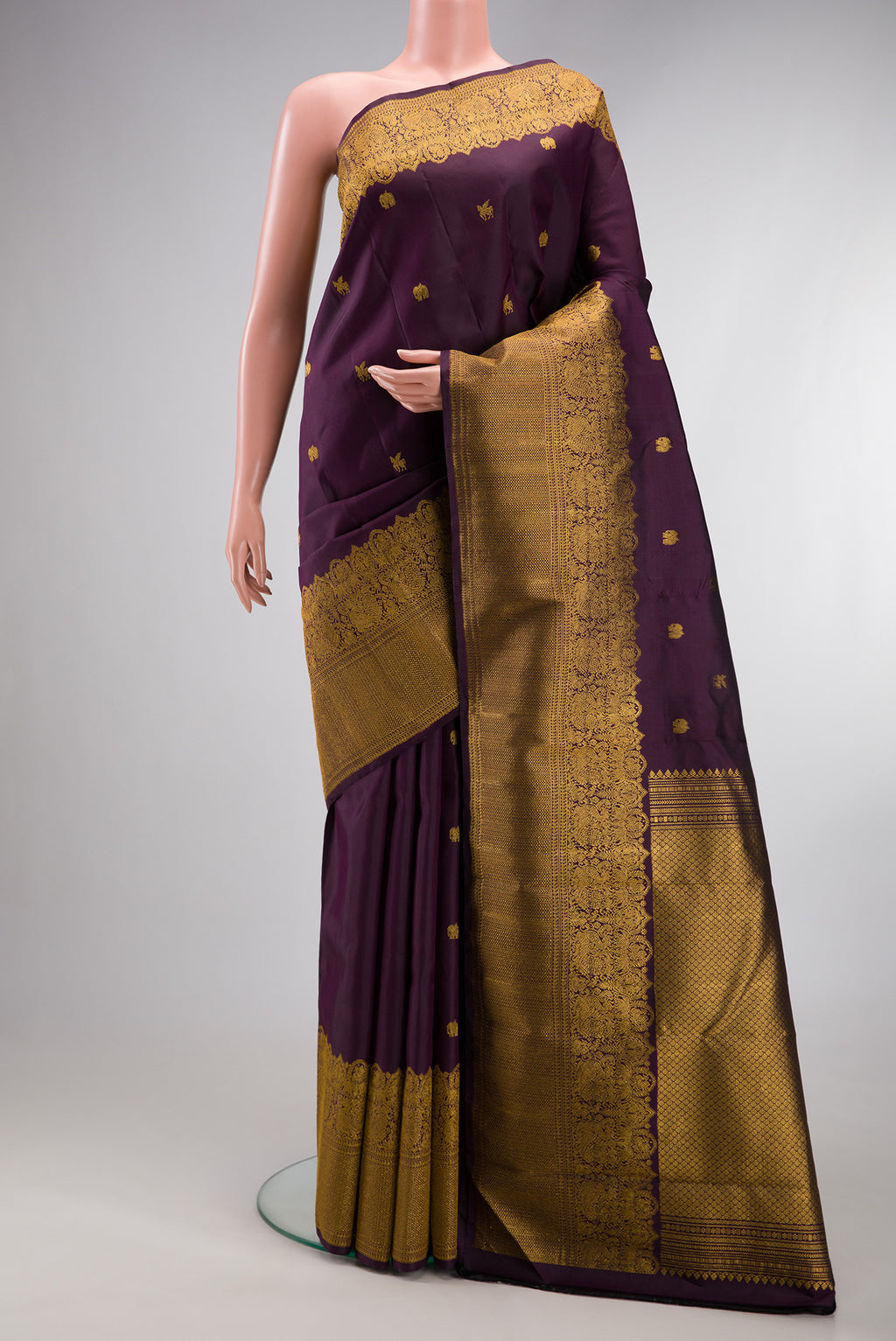 Burgundy Kanjivaram Silk Saree with Zari Butta on the body and Zari Border.  displayed on a mannequin