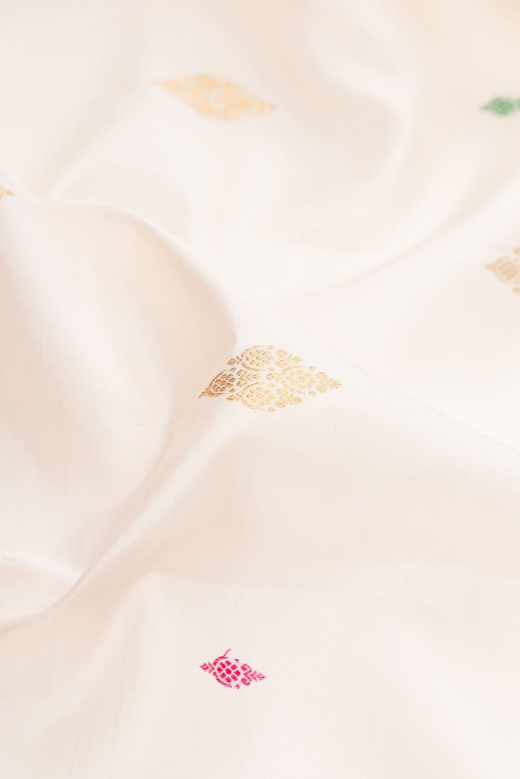 Close up of White Kanjivaram Silk Saree with Zari And Thread Butta on the body and Zari Border.  displaying folds