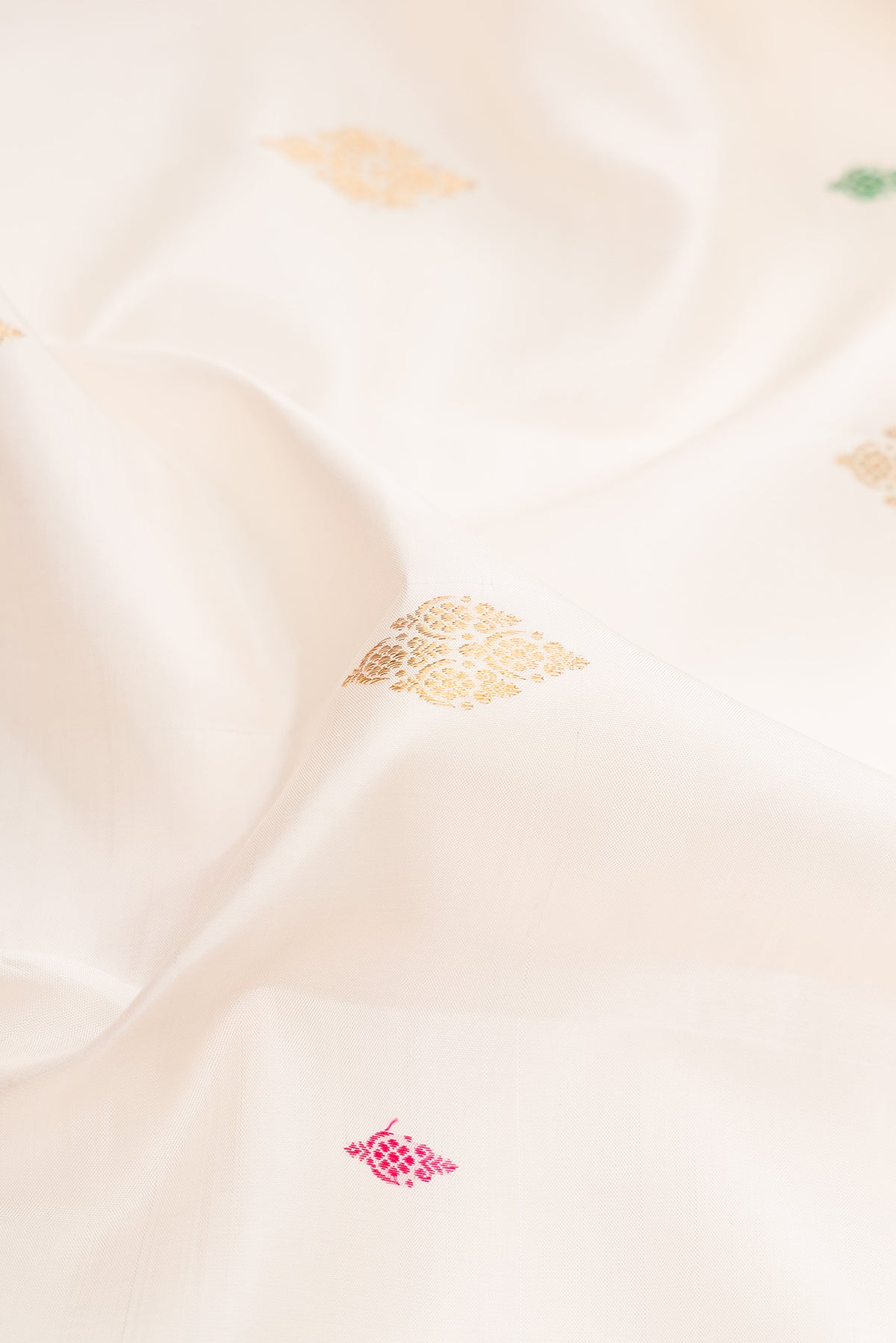 Close up of White Kanjivaram Silk Saree with Zari And Thread Butta on the body and Zari Border.  displaying folds