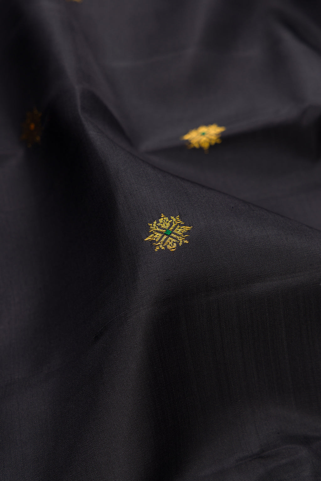 Close up of Black Kanjivaram Silk Saree with Zari Butta on the body and Zari Border.  displaying folds