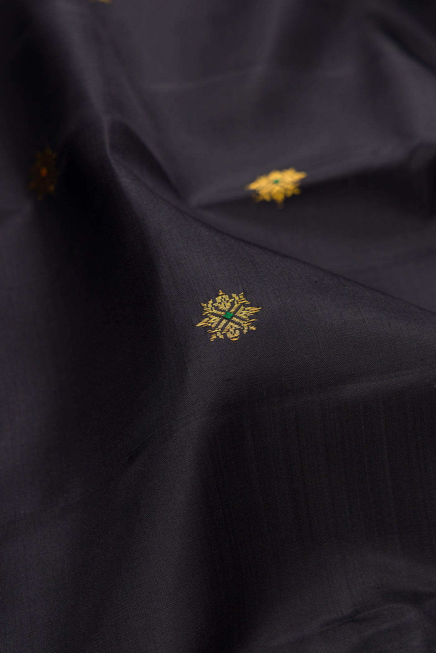 Close up of Black Kanjivaram Silk Saree with Zari Butta on the body and Zari Border.  displaying folds