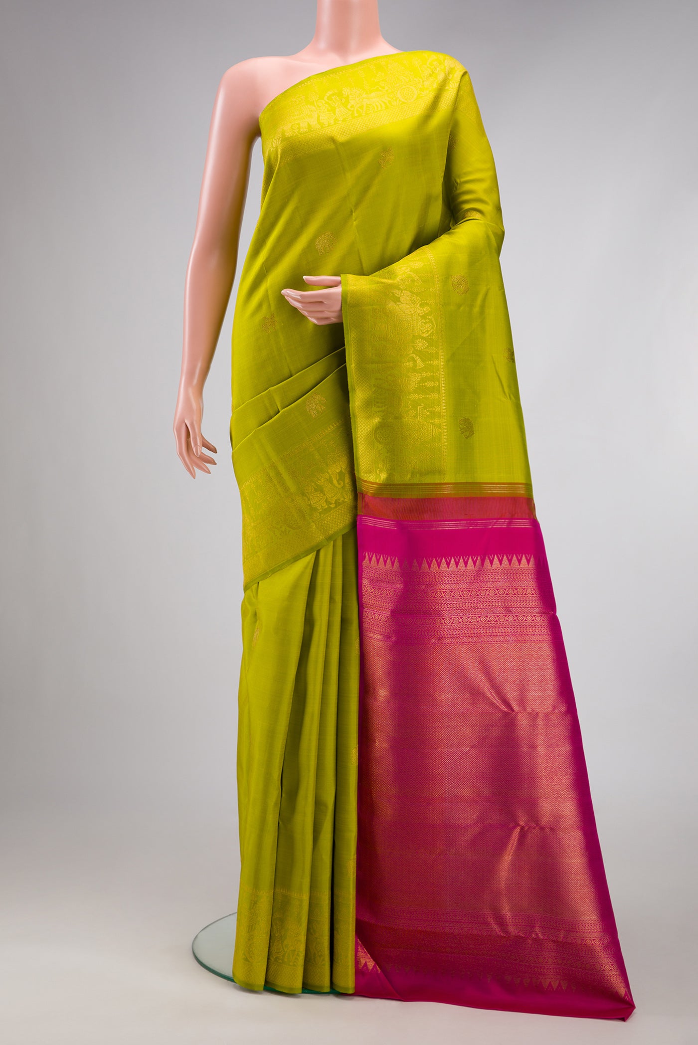 Parrot Green Kanchipuram Silk Saree with Zari Butta on the body and Zari Border.  displayed on a mannequin