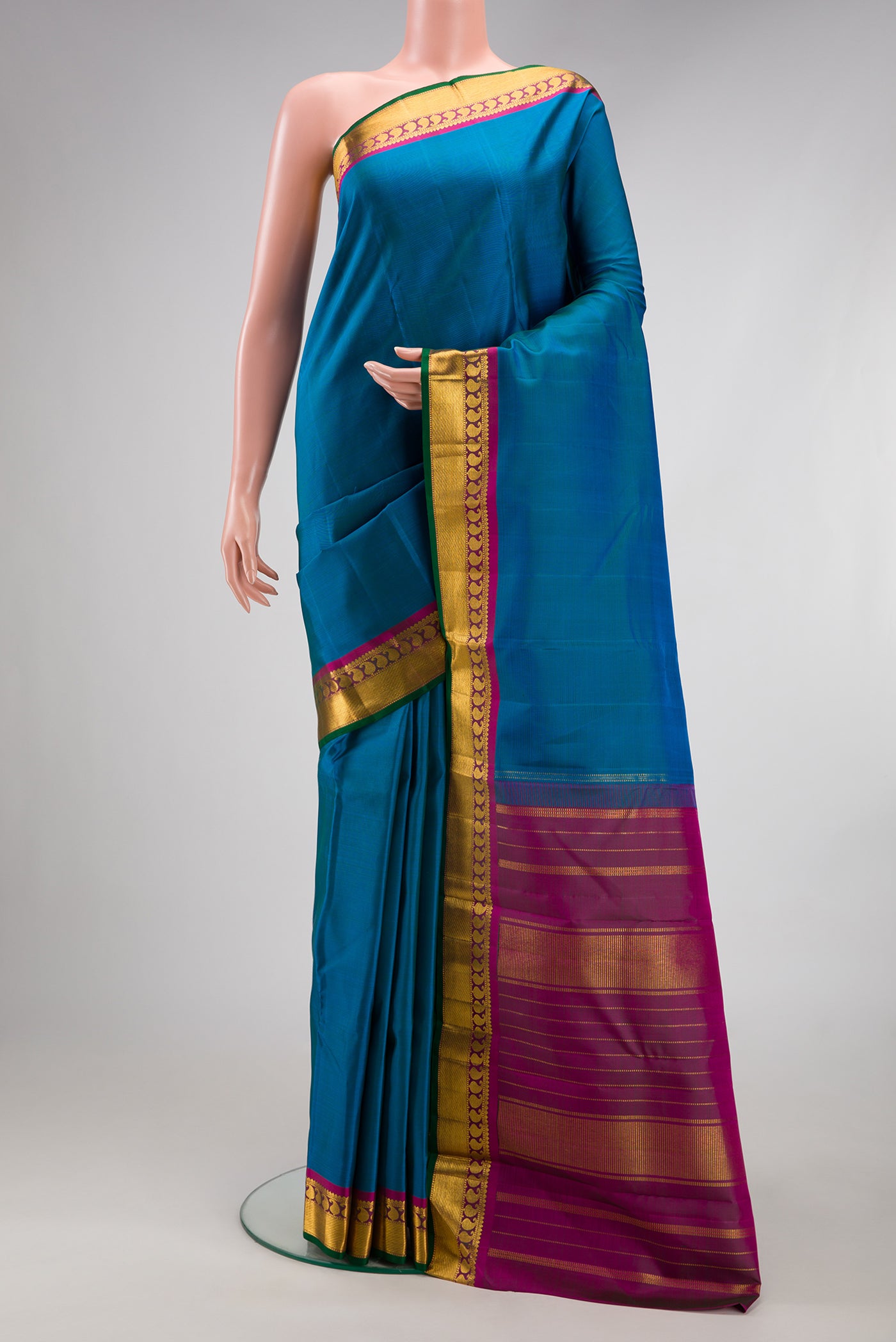 Peacock Blue Kanchipuram Silk Saree with Plain Body and Zari Border.  displayed on a mannequin