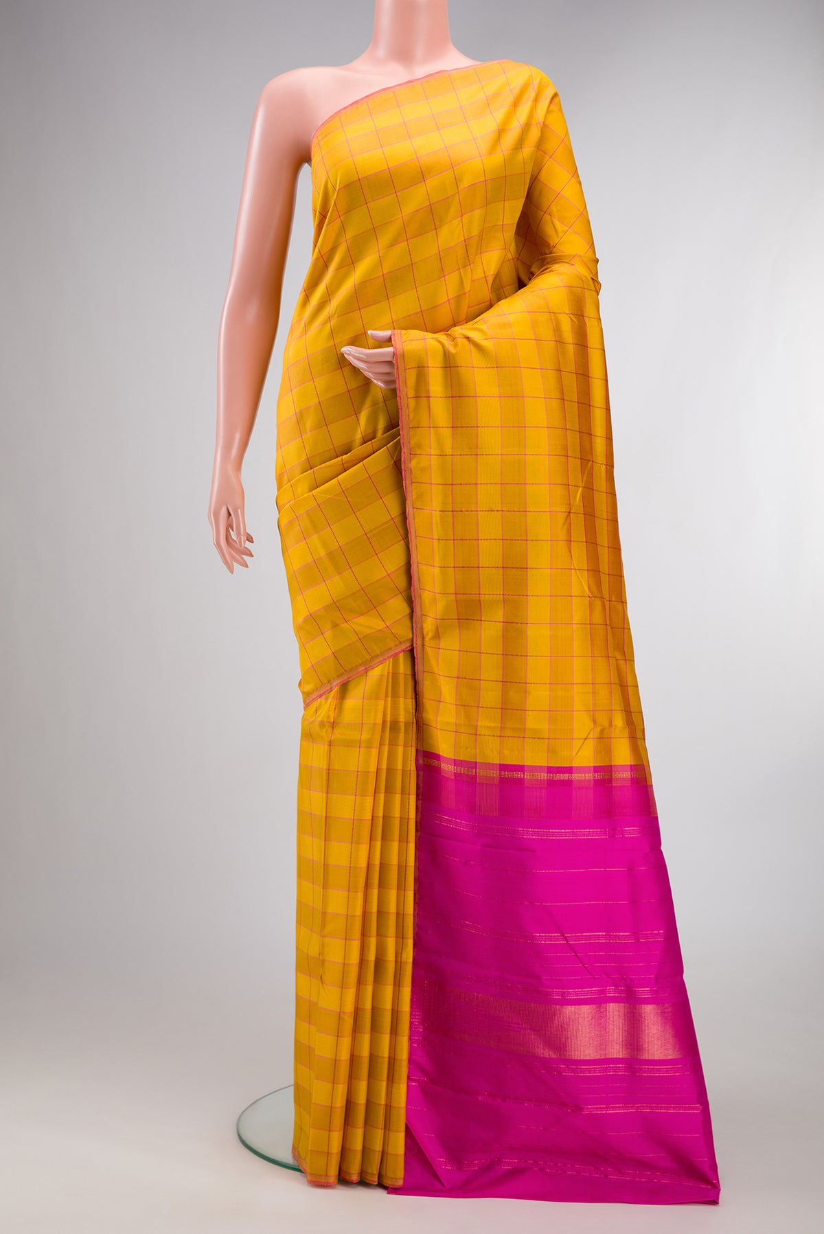Pure Silk Mustard Kanchipuram Saree with Checked design on the body and Thin Zari Line.  displayed on a mannequin