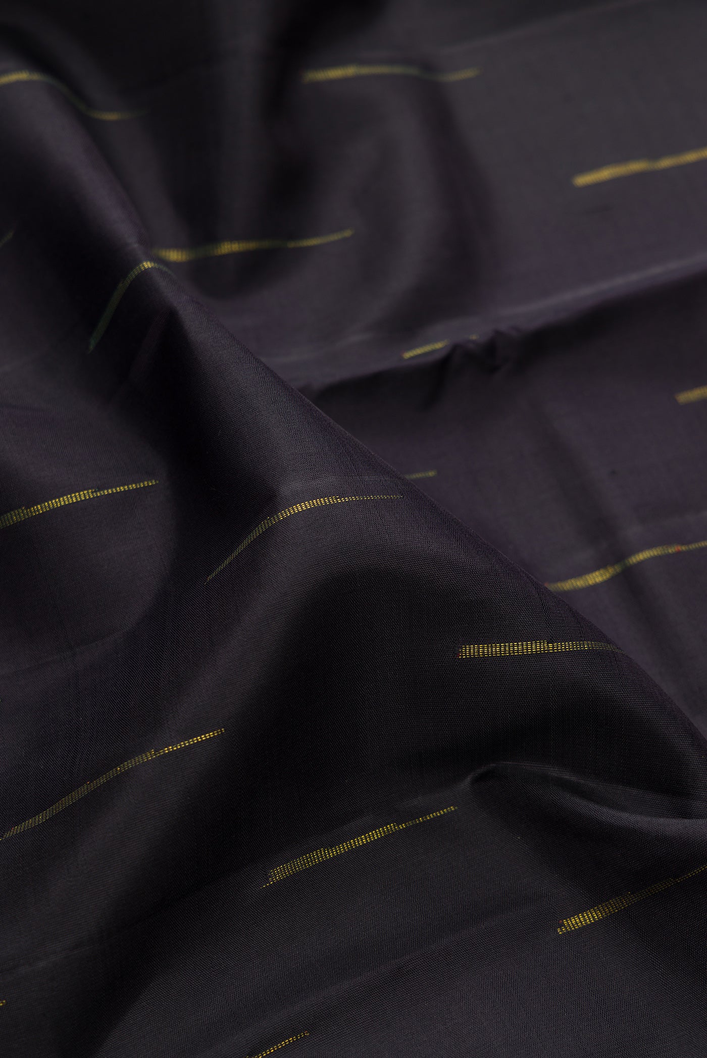 Close up of Black Kanchipuram Silk Saree with Zari Butta on the body and Ganga Jamuna Border.  displaying folds