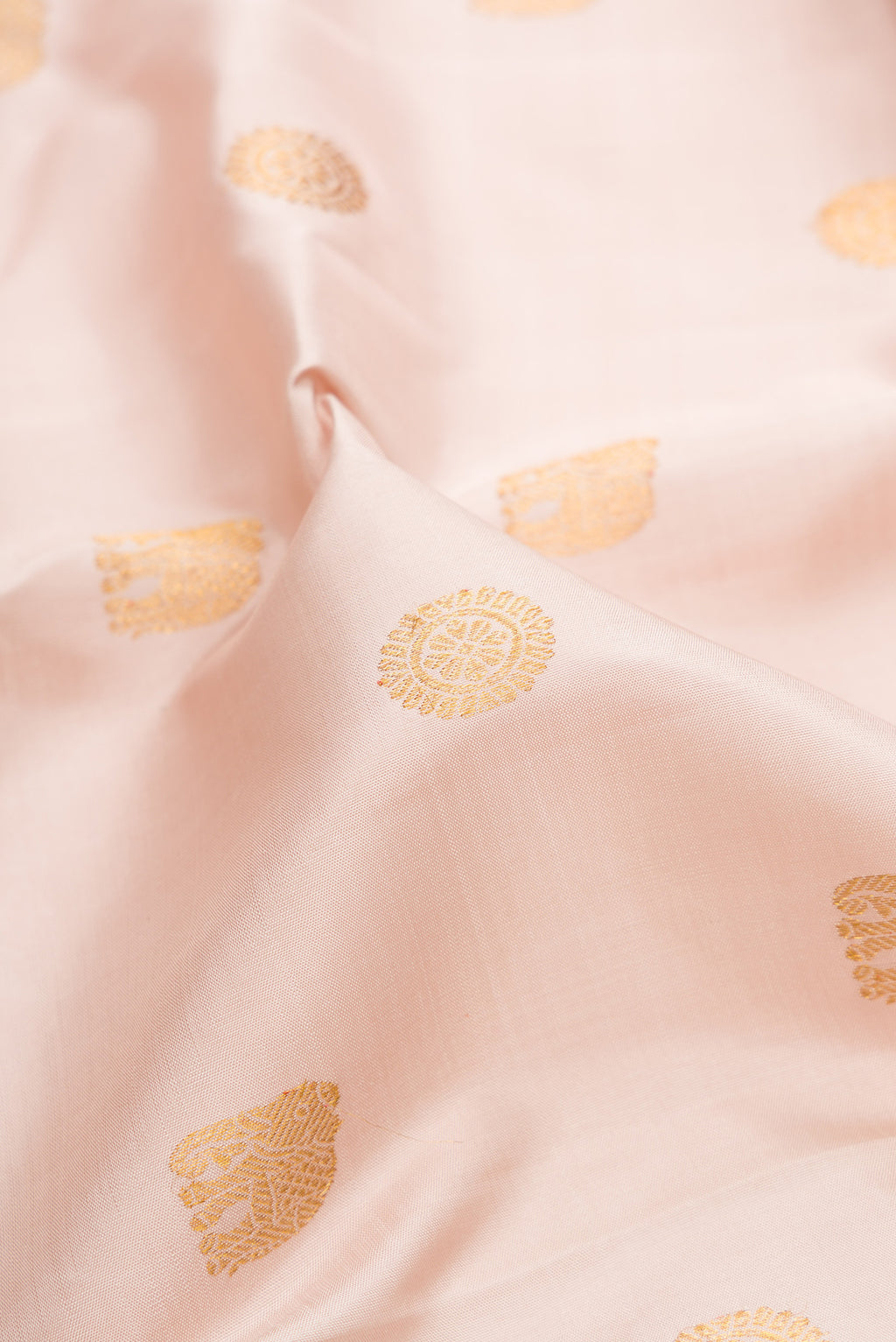 Close up of Pure Silk Rose Gold Kanjivaram Saree with Zari Butta on the body and Zari Border.  displaying folds
