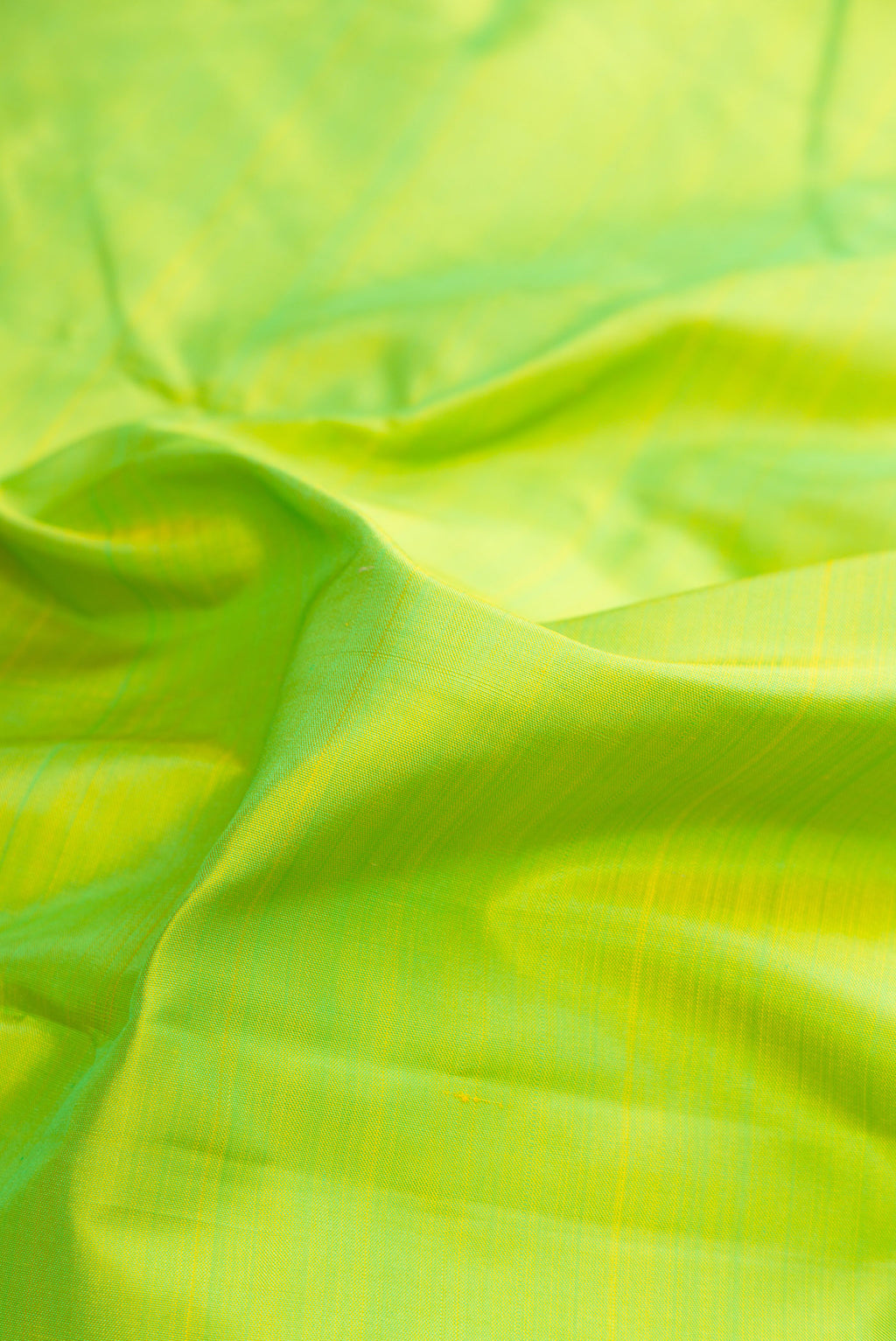 Close up of Pure Silk Pure Zari Parrot Green Kanjivaram Saree with Plain Body and One Side Border.  displaying folds