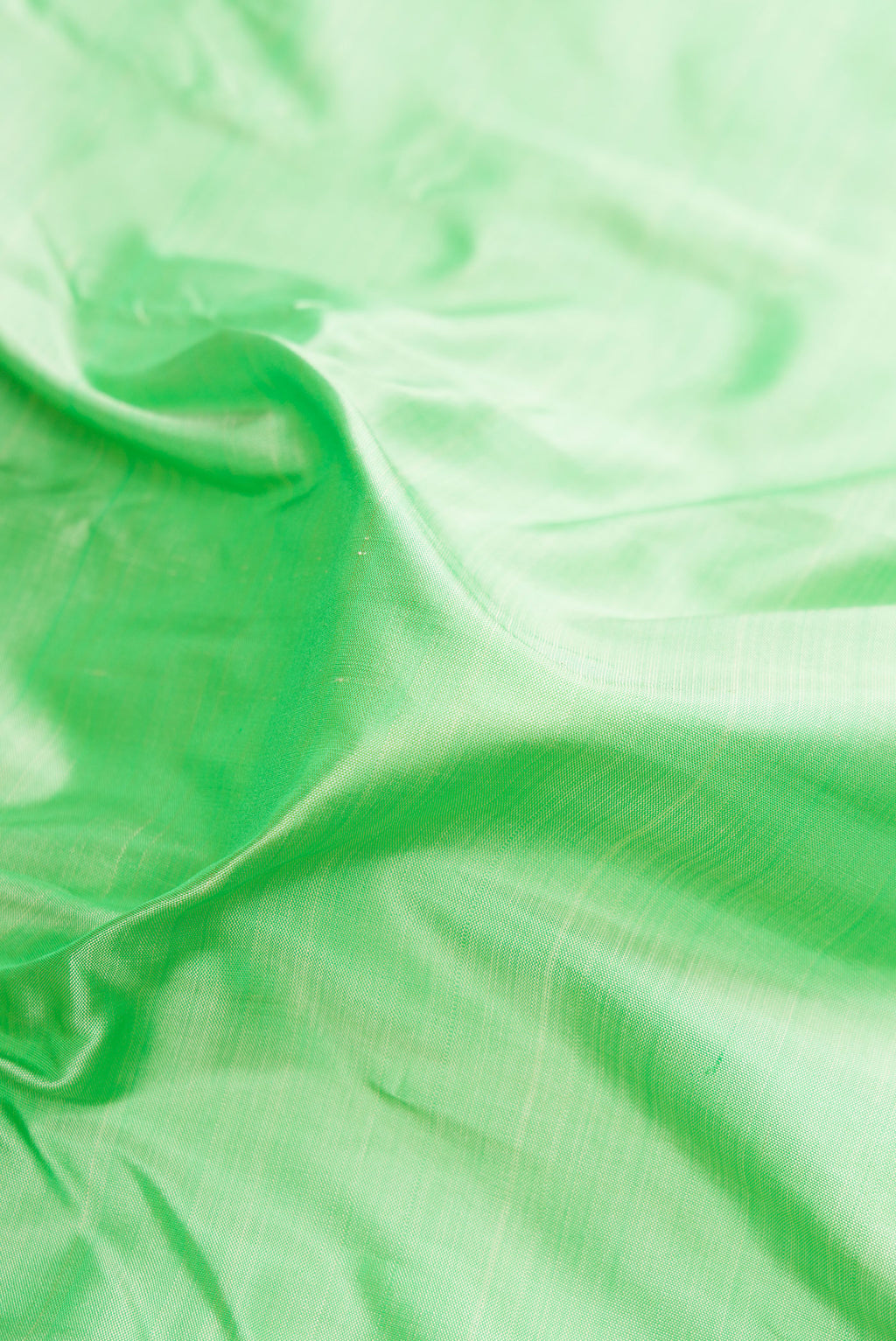Close up of Pure Silk Pure Zari Pista Green Kanjivaram Saree with Plain Body and One Side Border.  displaying folds