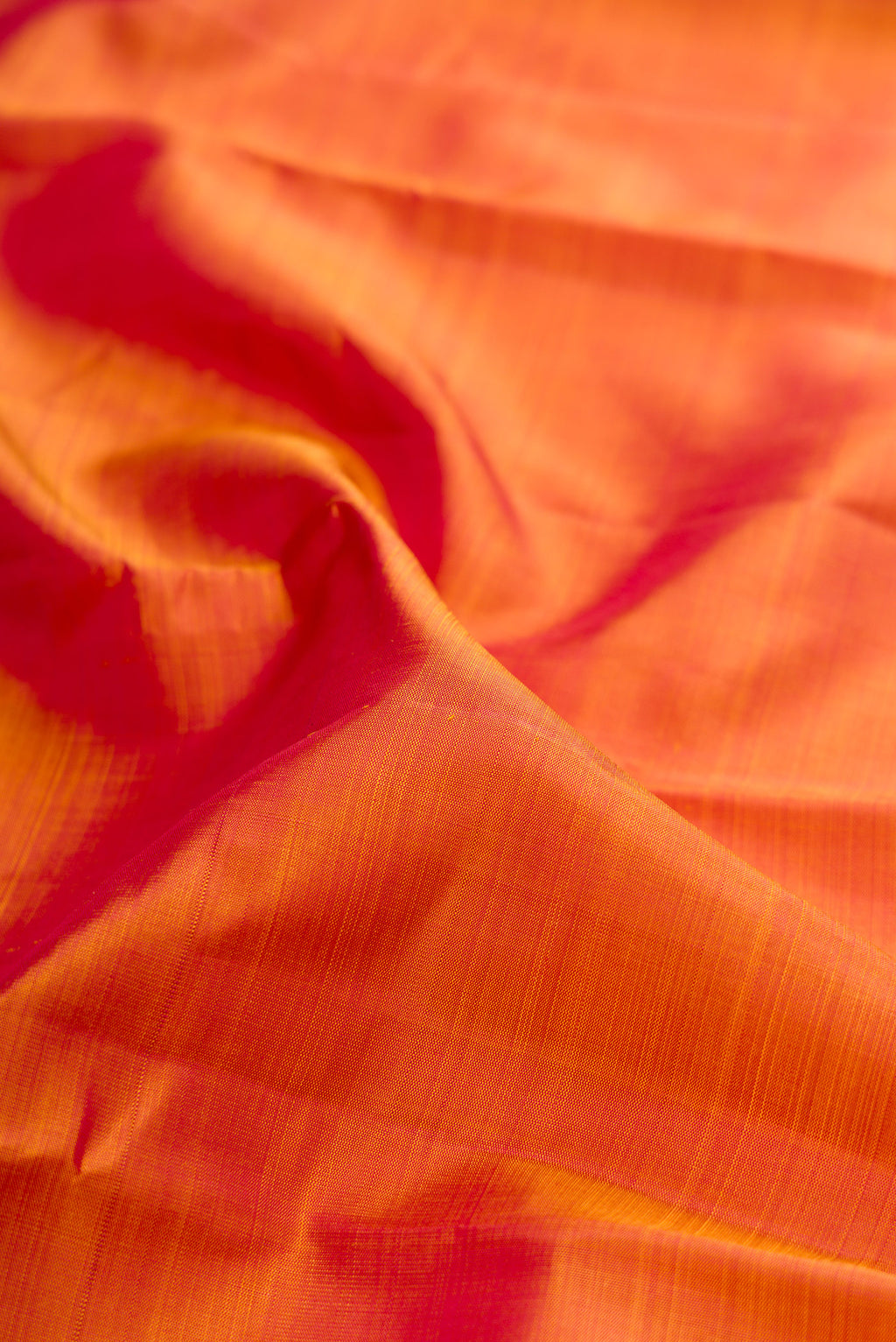 Close up of Pinkish Yellow Dual Tone Kanjivaram Silk Saree with Plain Body and Zari Border.  displaying folds
