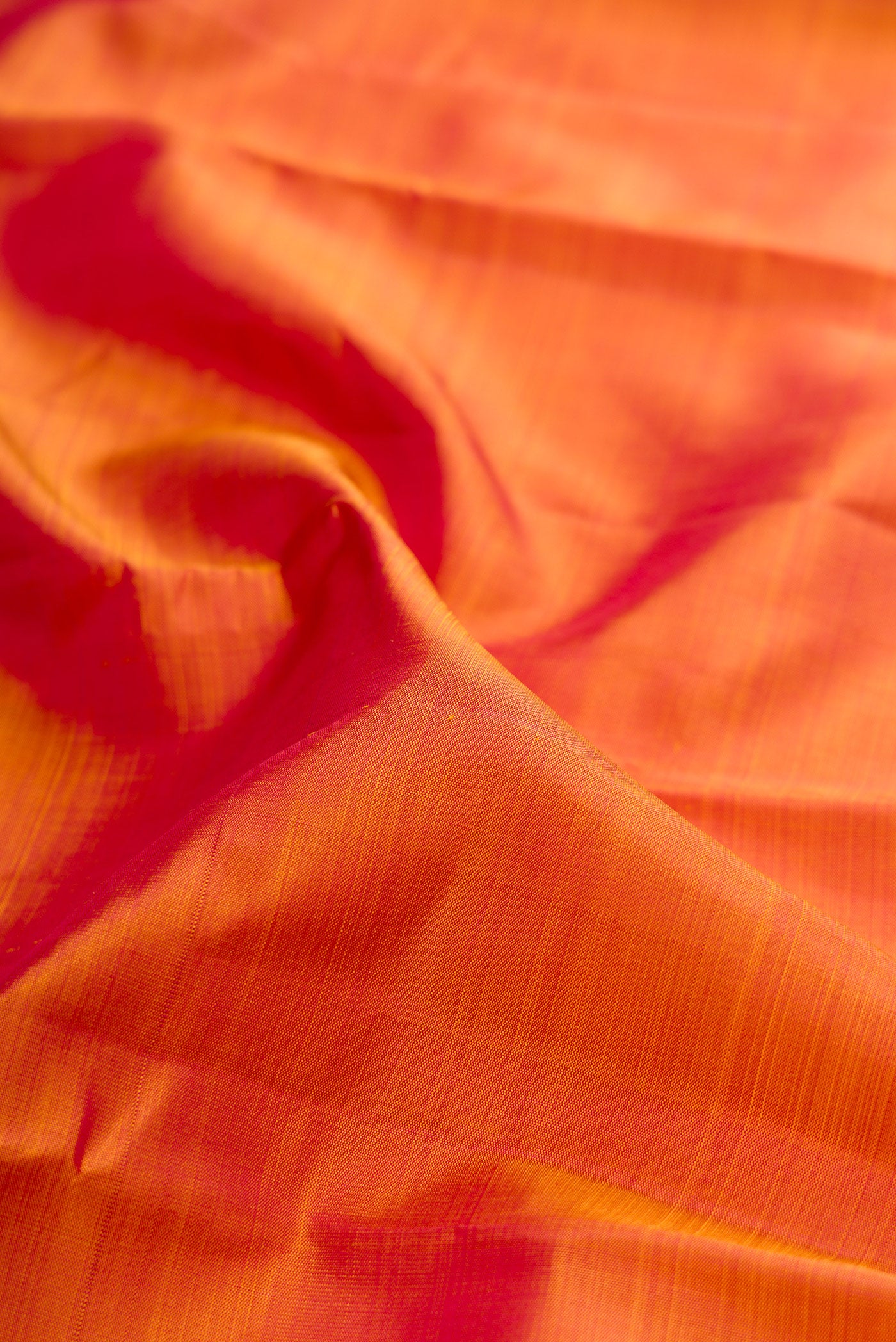 Close up of Pinkish Yellow Dual Tone Kanjivaram Silk Saree with Plain Body and Zari Border.  displaying folds