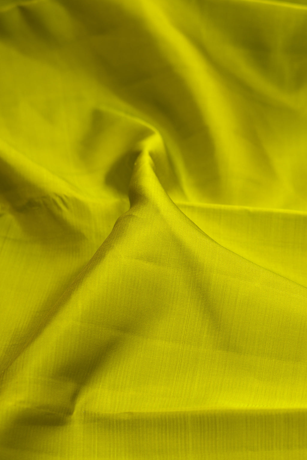 Close up of Parrot Green Kanjivaram Silk Saree with Plain Body and Zari Border.  displaying folds
