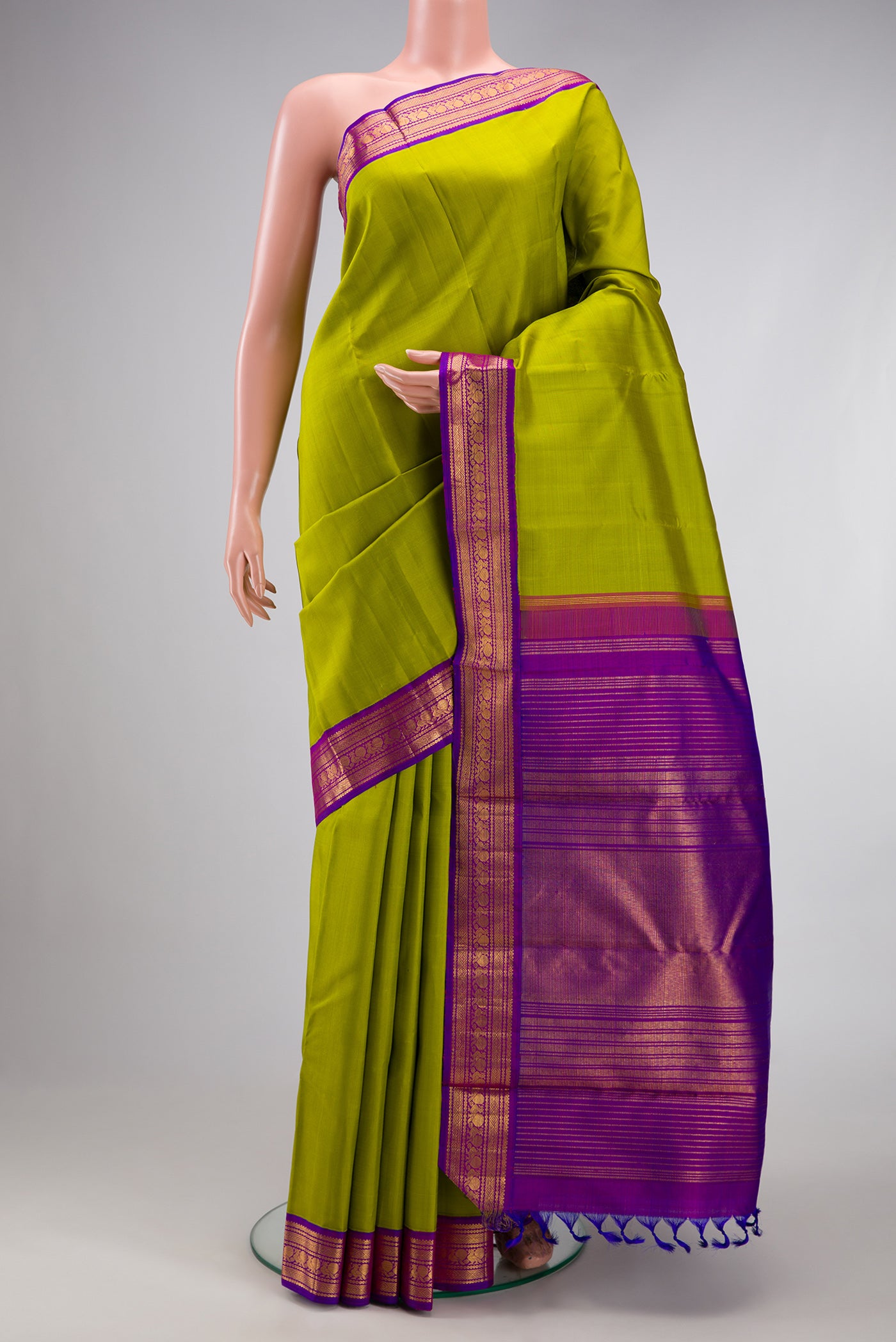 Parrot Green Kanjivaram Silk Saree with Plain Body and Zari Border.  displayed on a mannequin