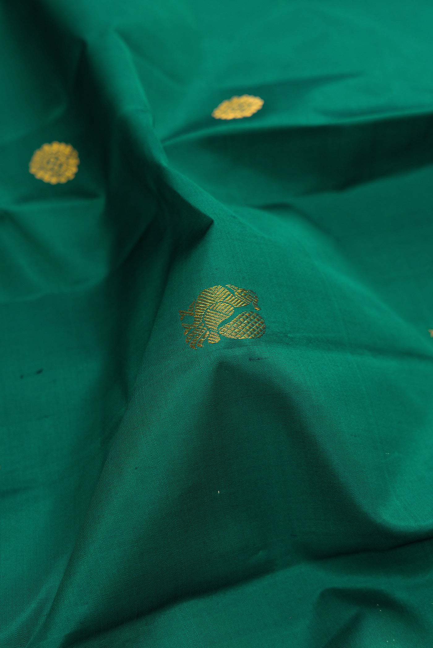 Close up of Teal Kanchipuram Silk Saree with Zari Butta on the body and Zari Border.  displaying folds
