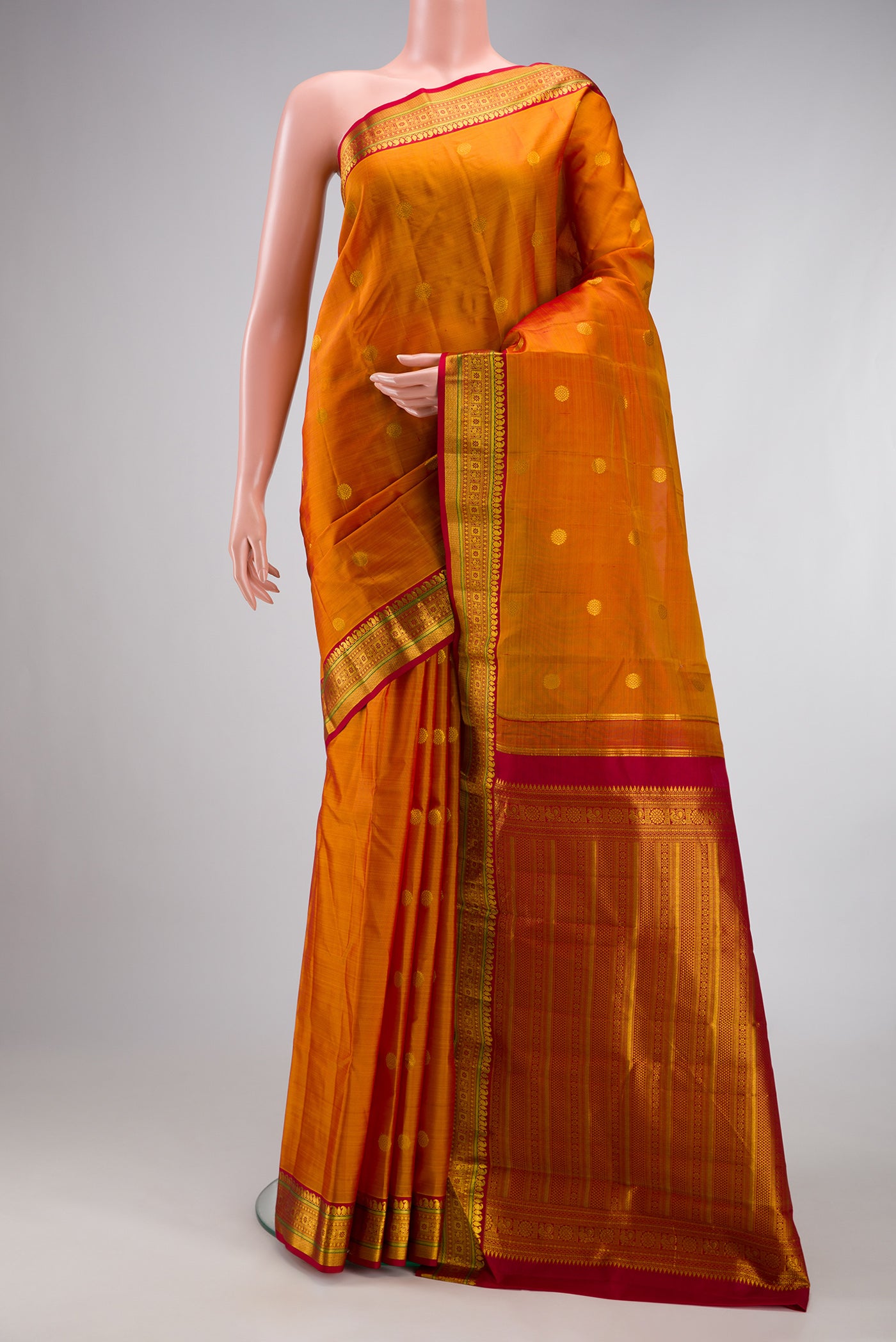Mustard Kanchipuram Silk Saree with Zari Butta on the body and Zari Border.  displayed on a mannequin