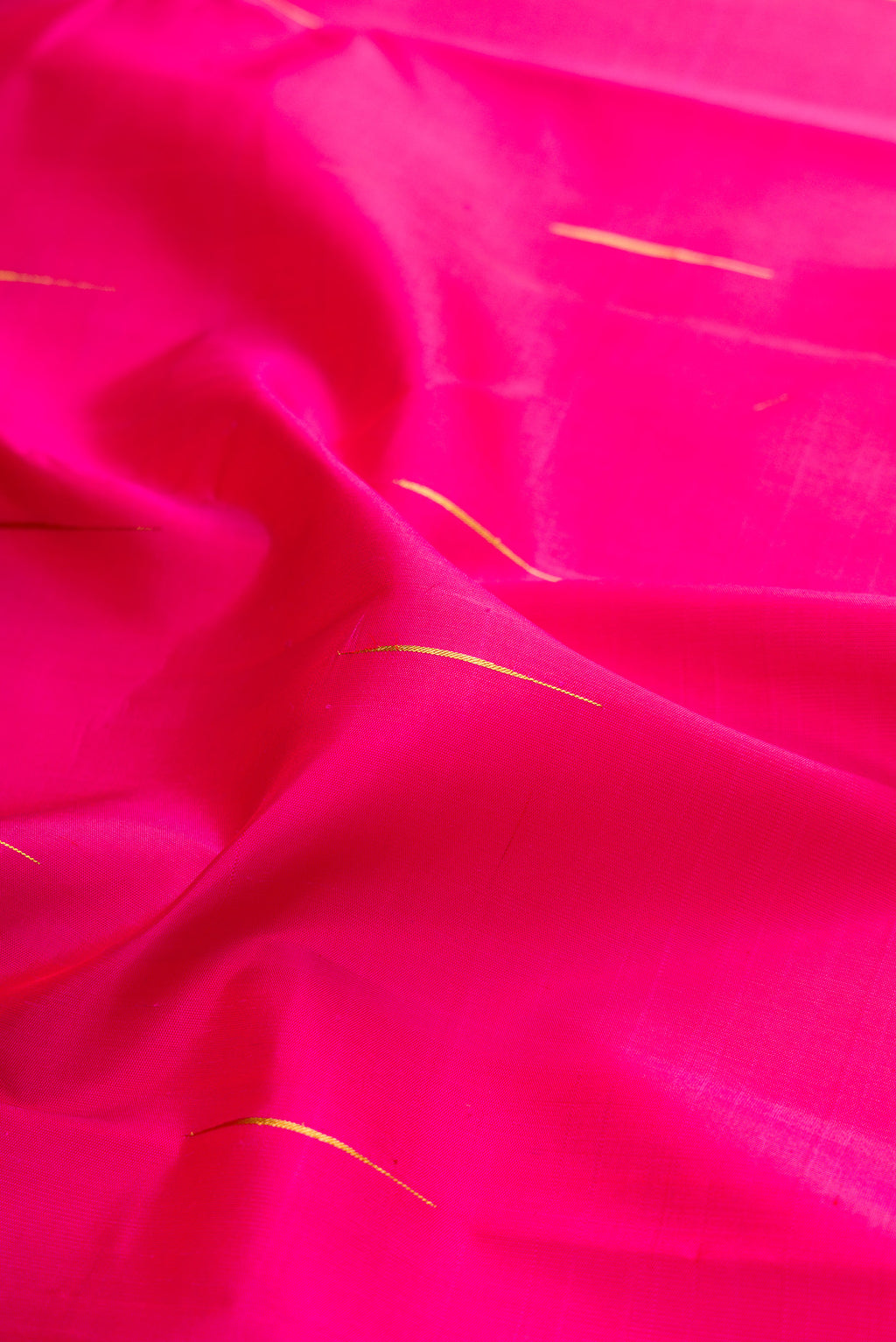 Close up of Dark Pink Kanjivaram Silk Saree with Zari Butta on the body and Zari Border.  displaying folds