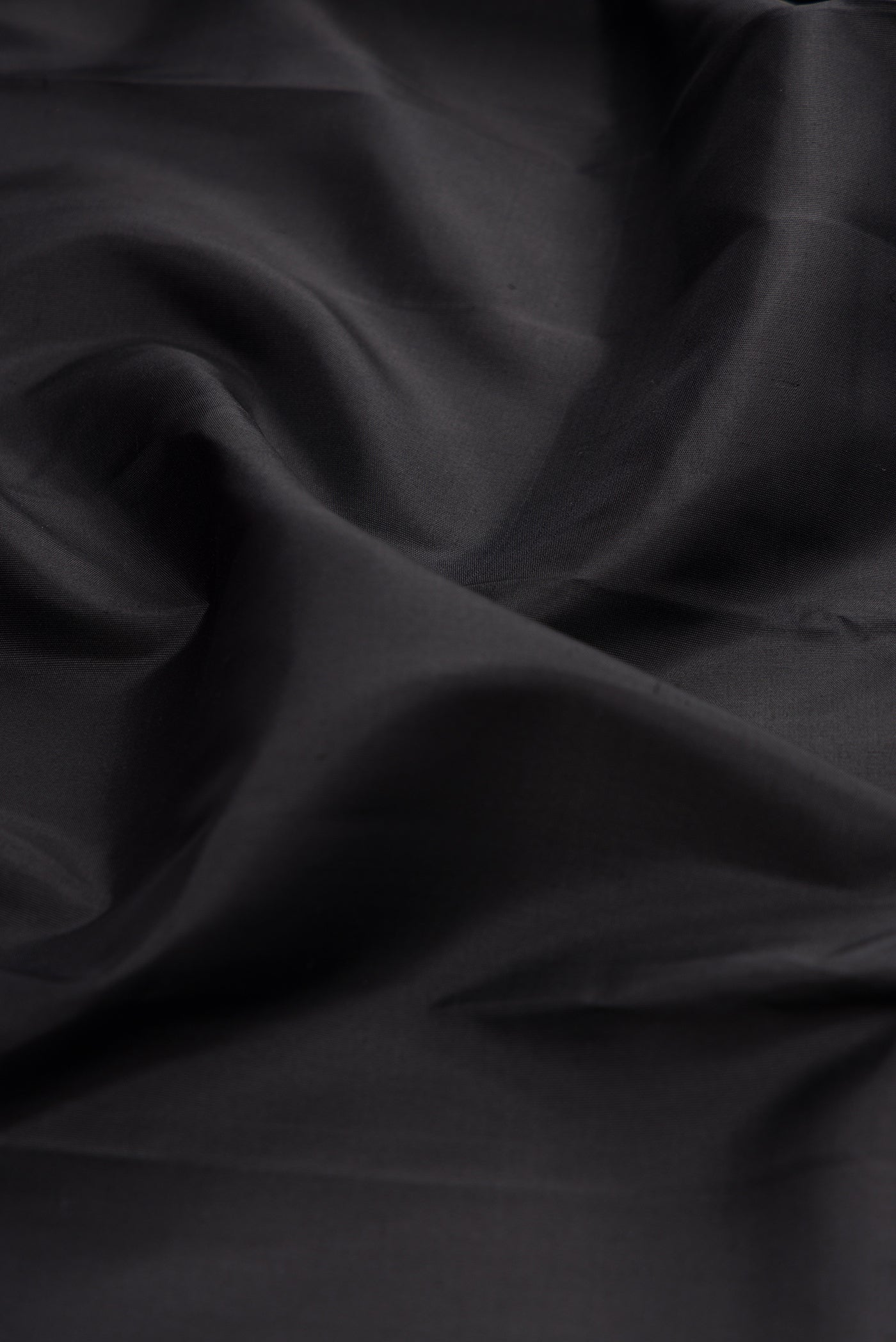 Close up of Black Kanchipuram Silk Saree with Plain Body and Zari Border.  displaying folds