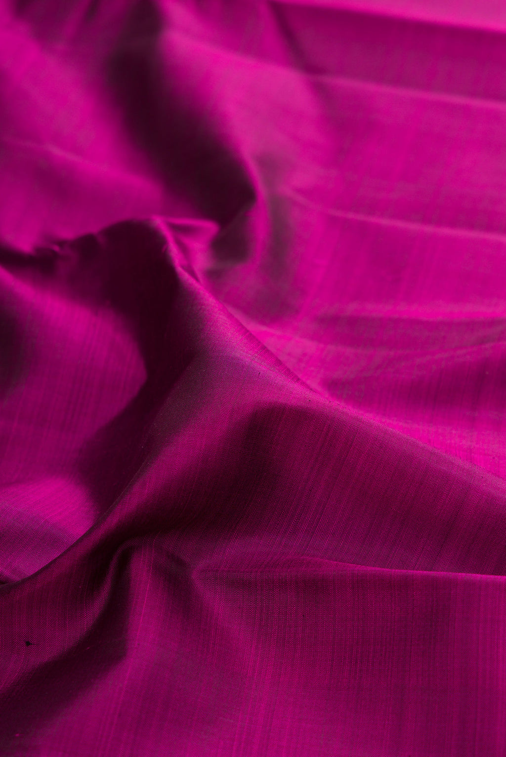 Close up of Magenta Kanjivaram Silk Saree with Plain Body and Zari Border.  displaying folds