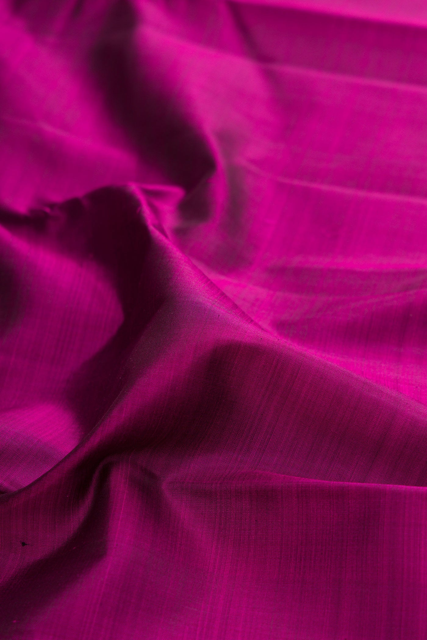 Close up of Magenta Kanjivaram Silk Saree with Plain Body and Zari Border.  displaying folds
